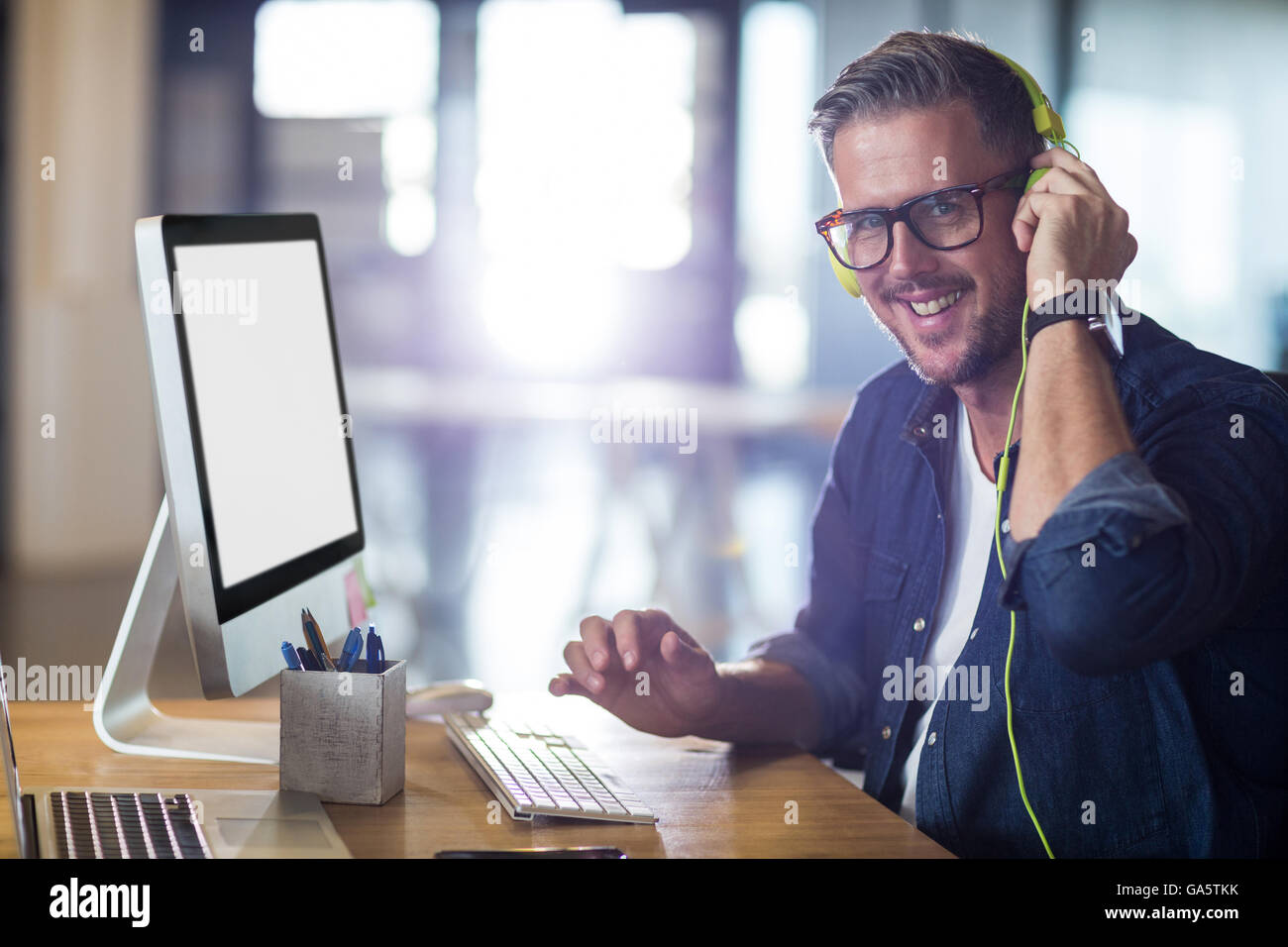 Portrait of smiling man with headphones in office Stock Photo