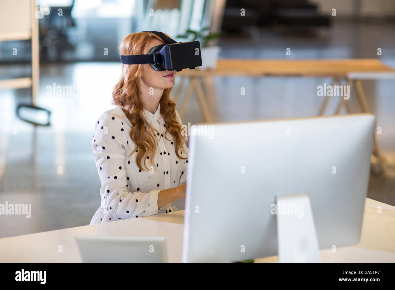 Businesswoman using virtual reality headset in office Stock Photo