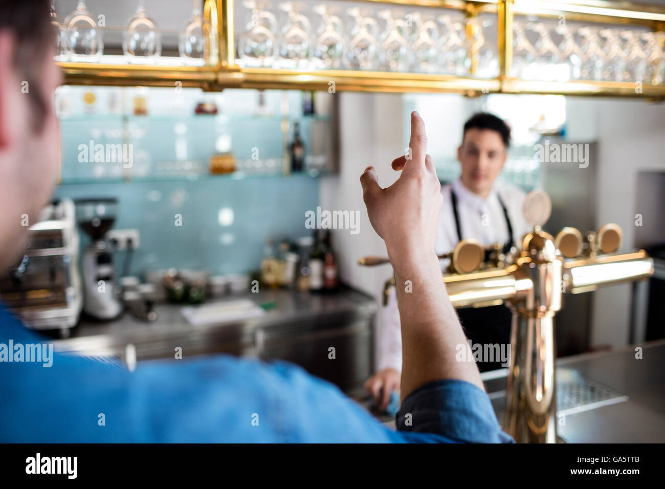 Man gesturing while talking with bartender Stock Photo