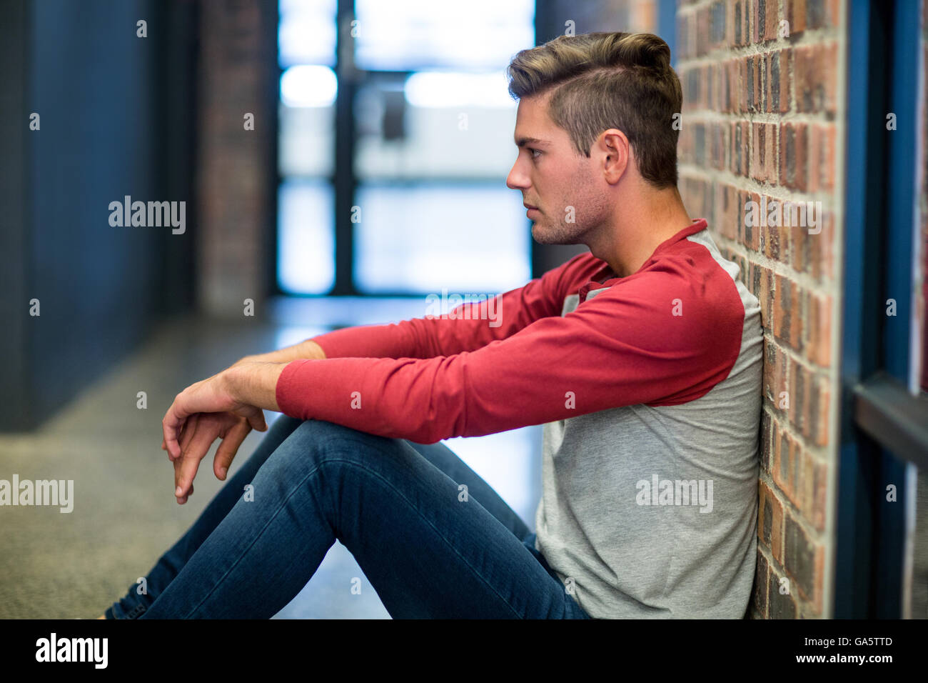 Stressed man sitting by wall Stock Photo