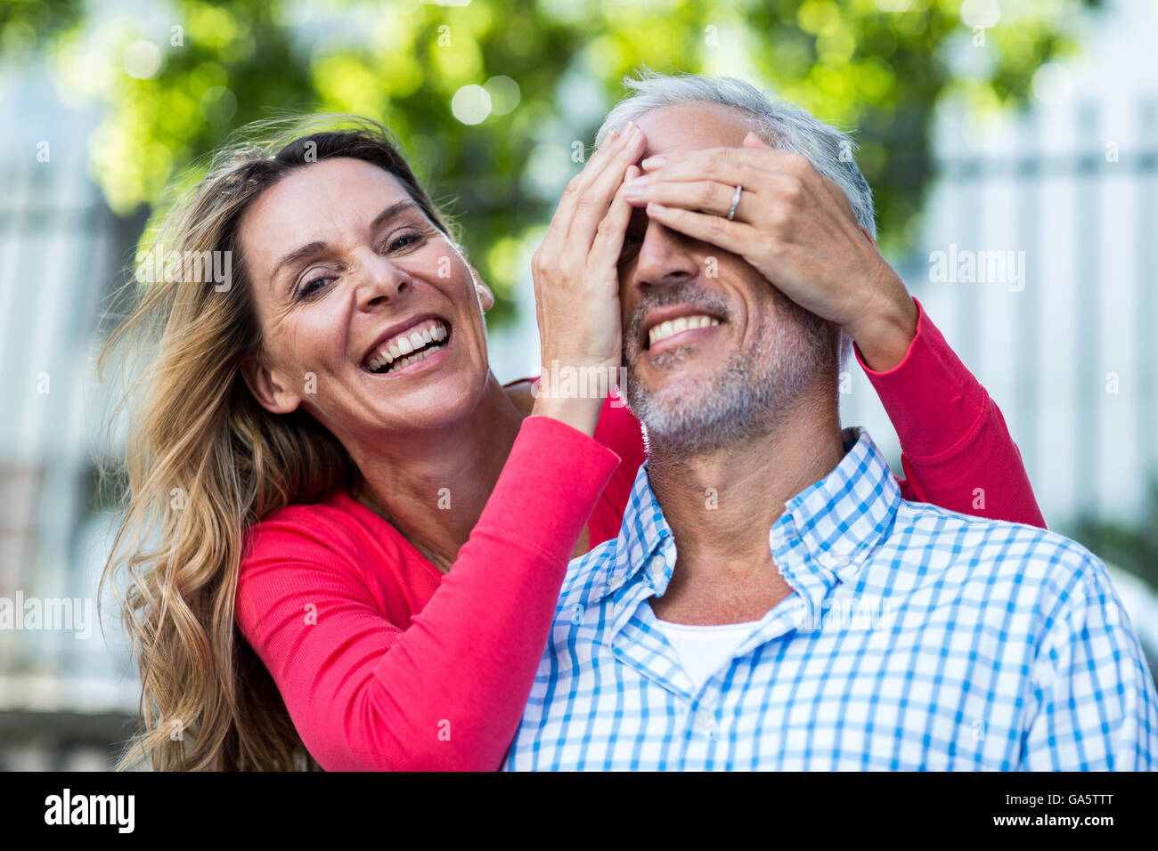 Mature woman covering eyes of man Stock Photo