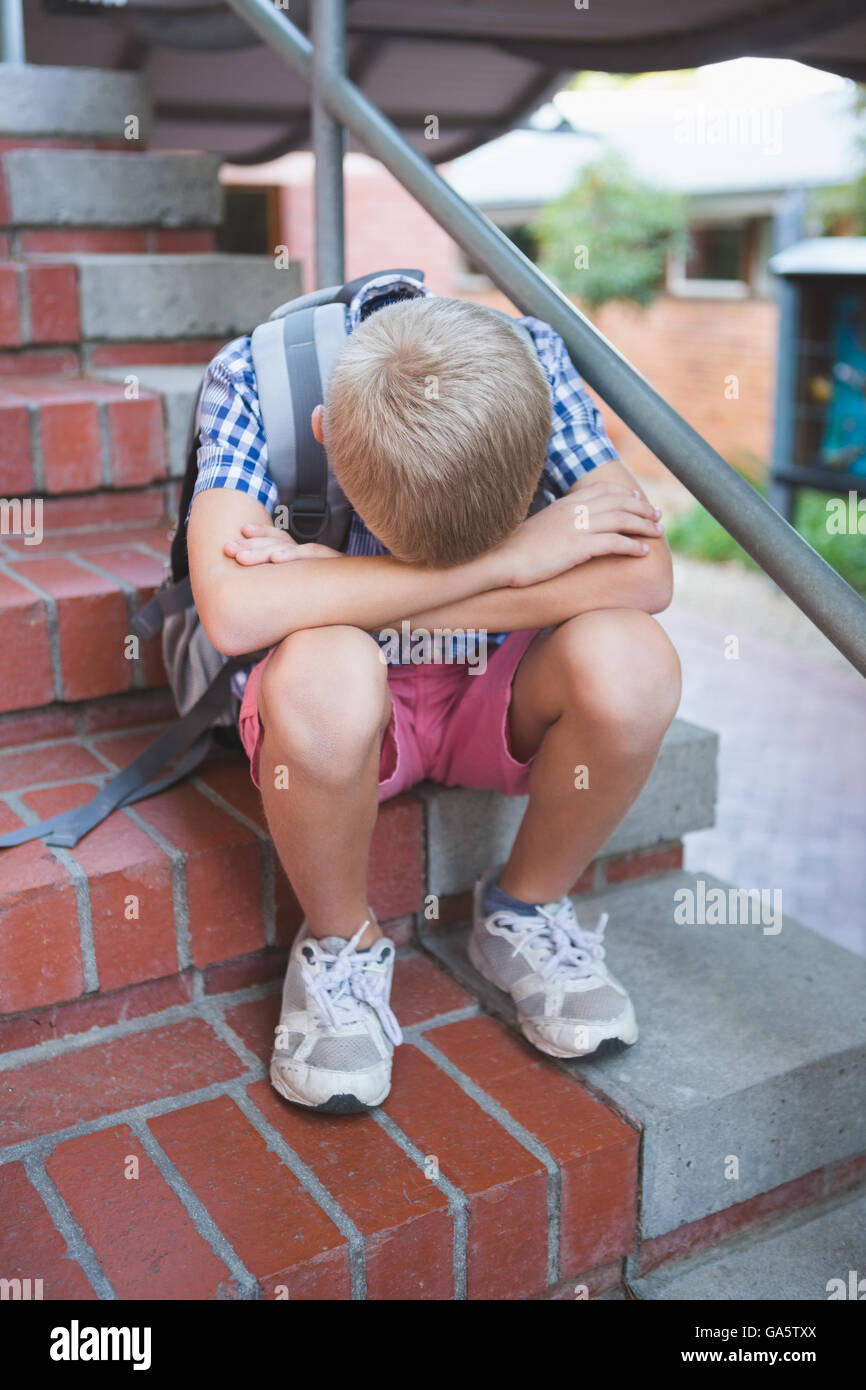 Sad schoolboy sitting alone on staircase Stock Photo