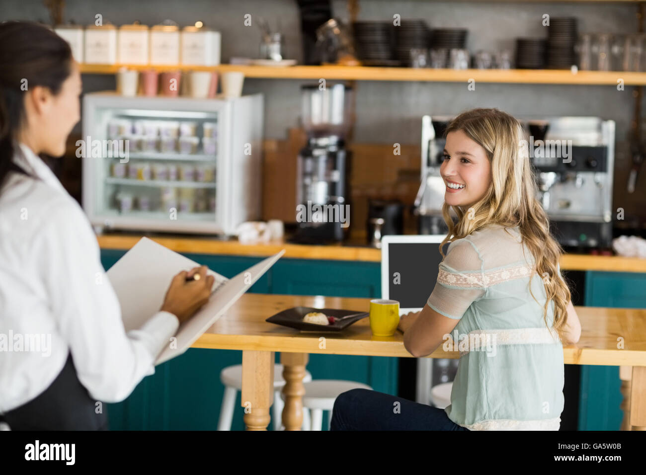 Woman ordering coffee from waitress Stock Photo
