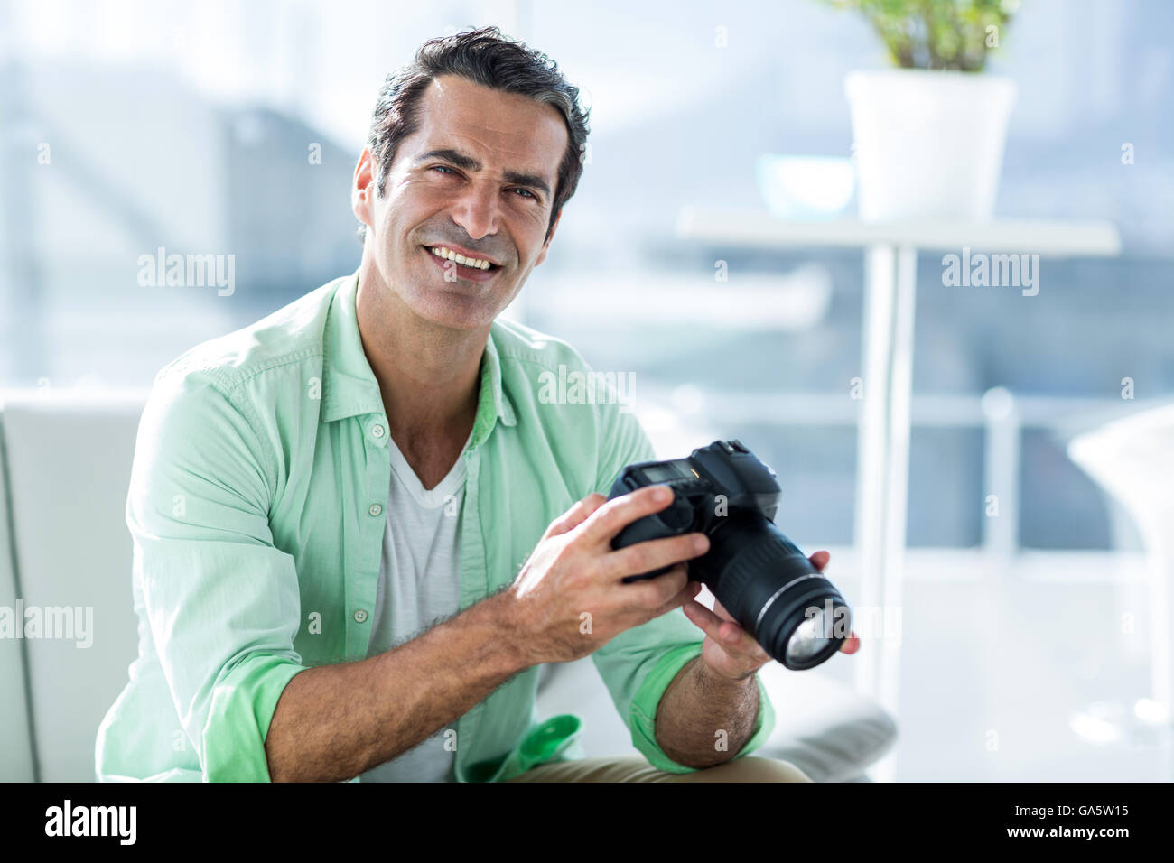 Mid adult man holding camera at home Stock Photo