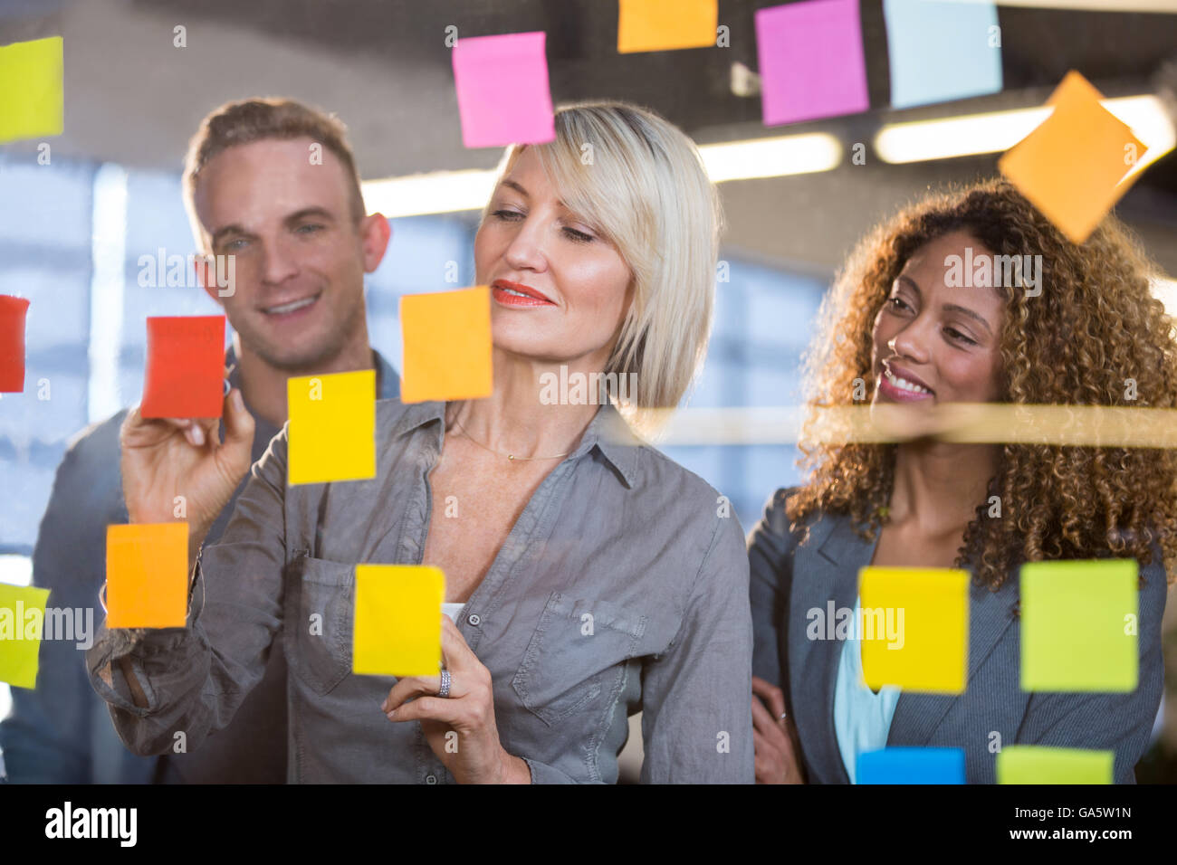 Businesswoman explaining to colleagues over sticky notes Stock Photo