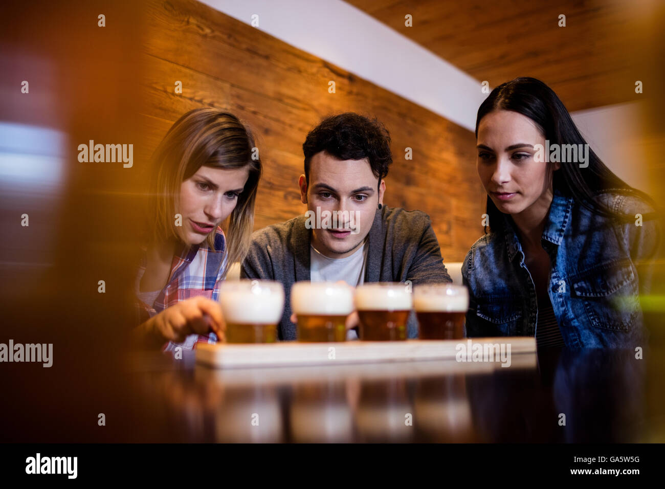 Friends looking at beer glasses on table Stock Photo