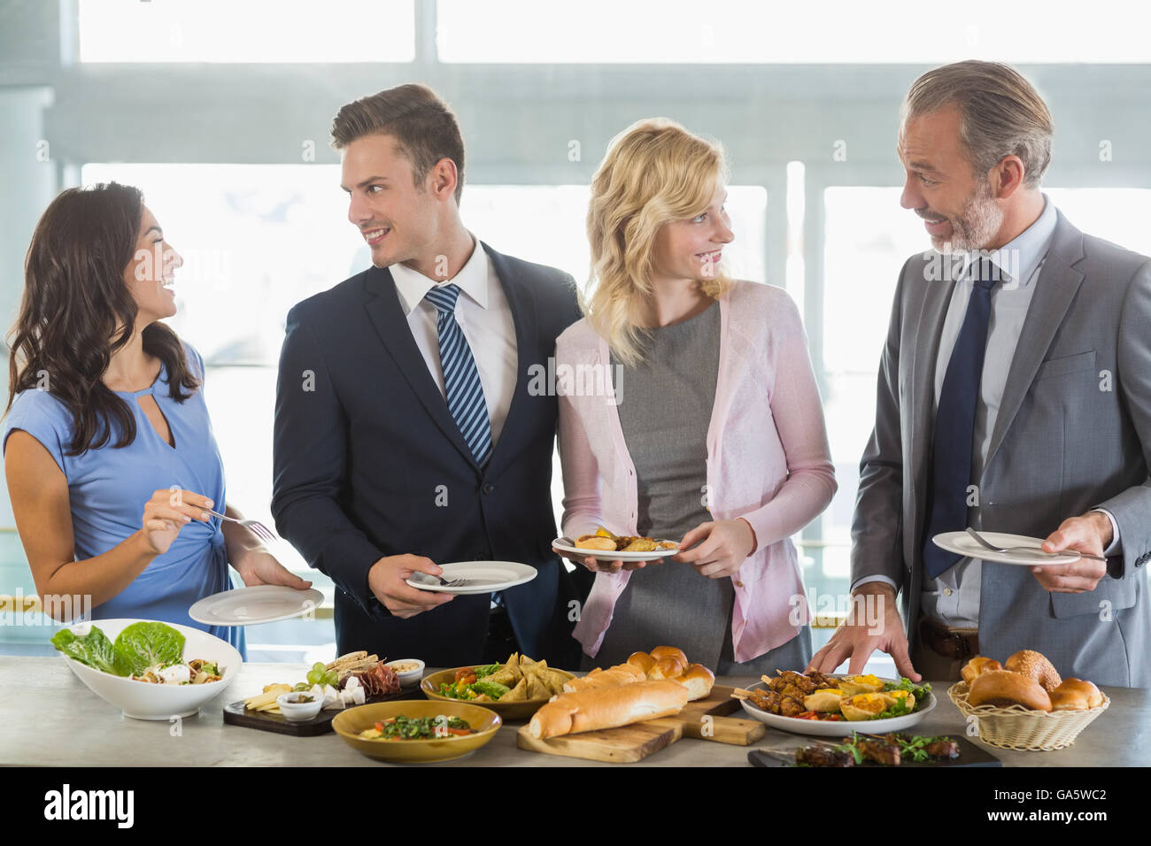 Business colleagues interacting while serving themselves at buffet ...