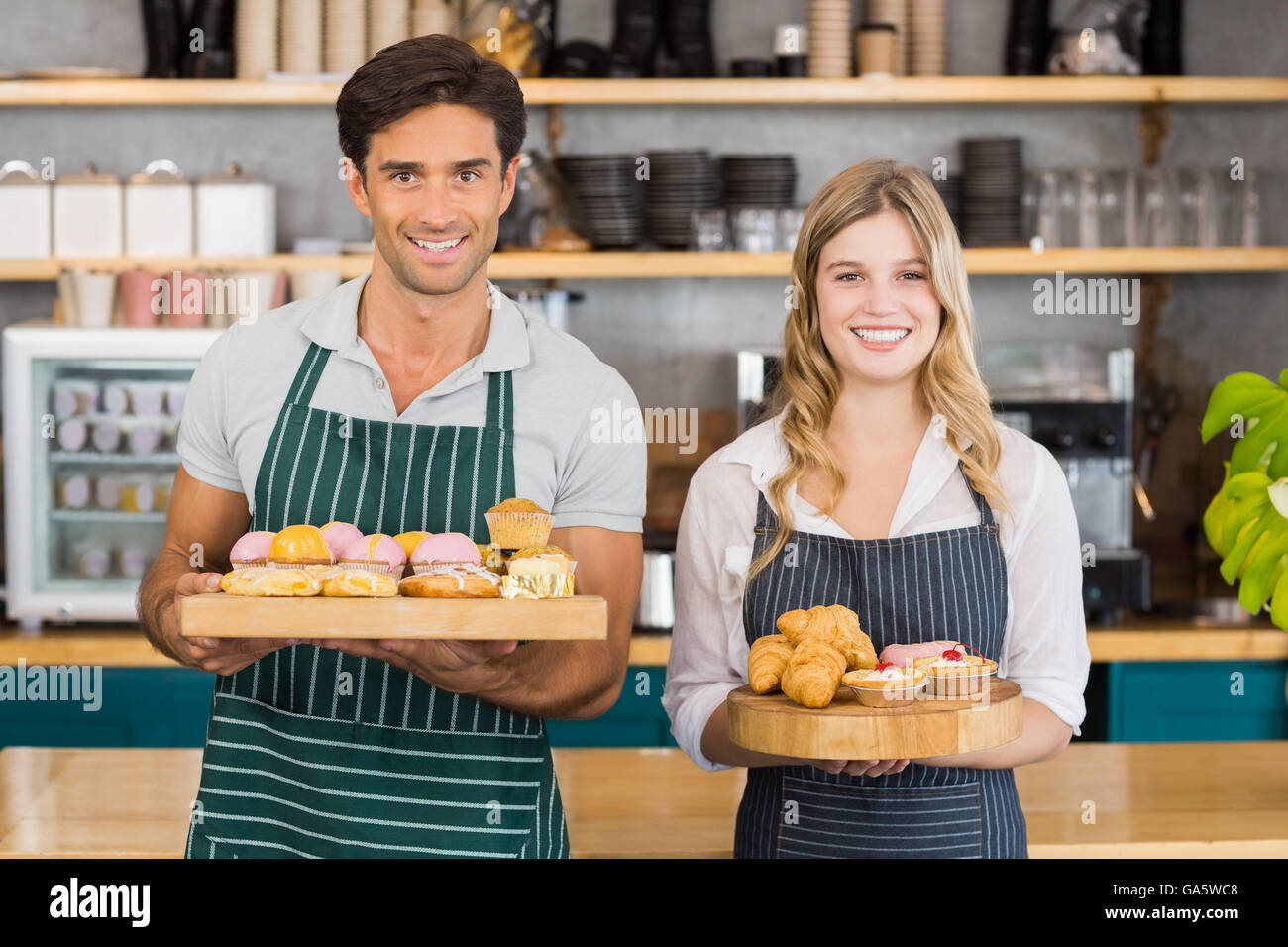 Portrait of waiter and waitress holding a tray of cupcakes Stock Photo