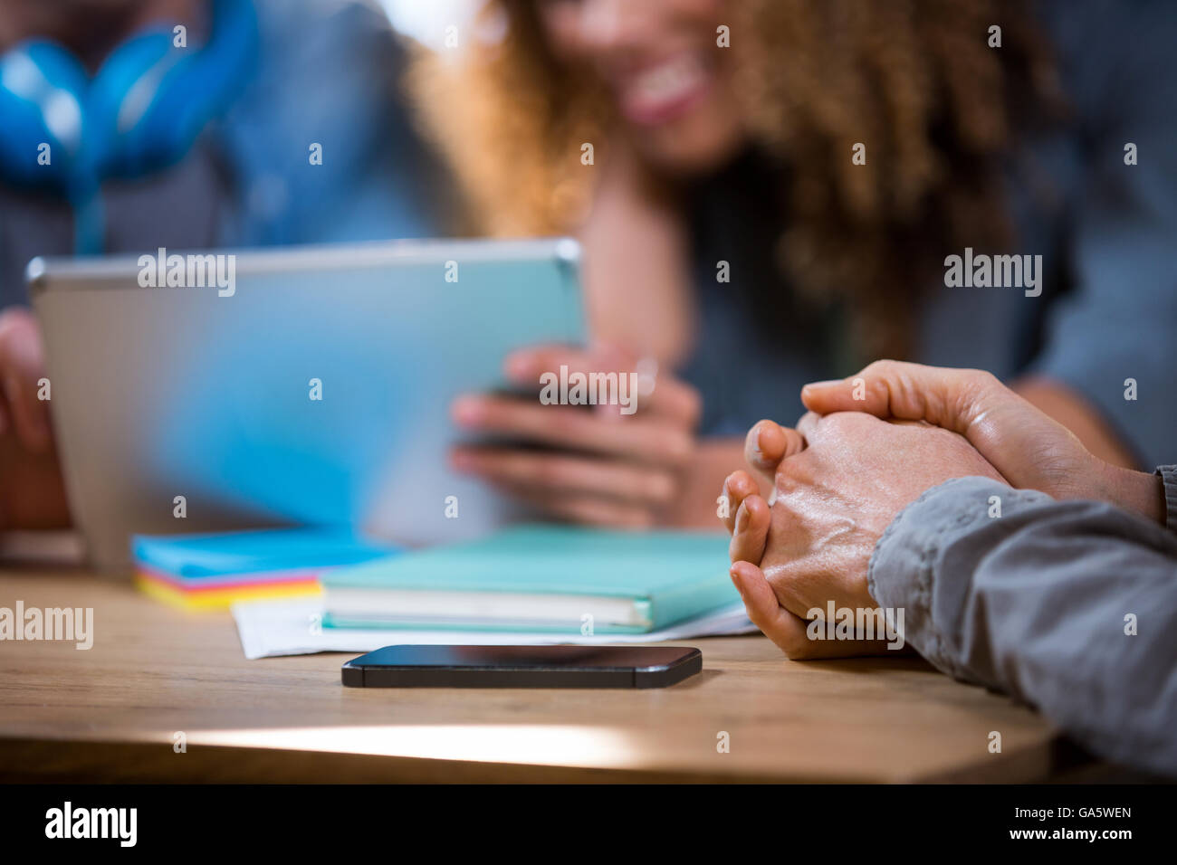 Businesswoman with hands clasped in office Stock Photo
