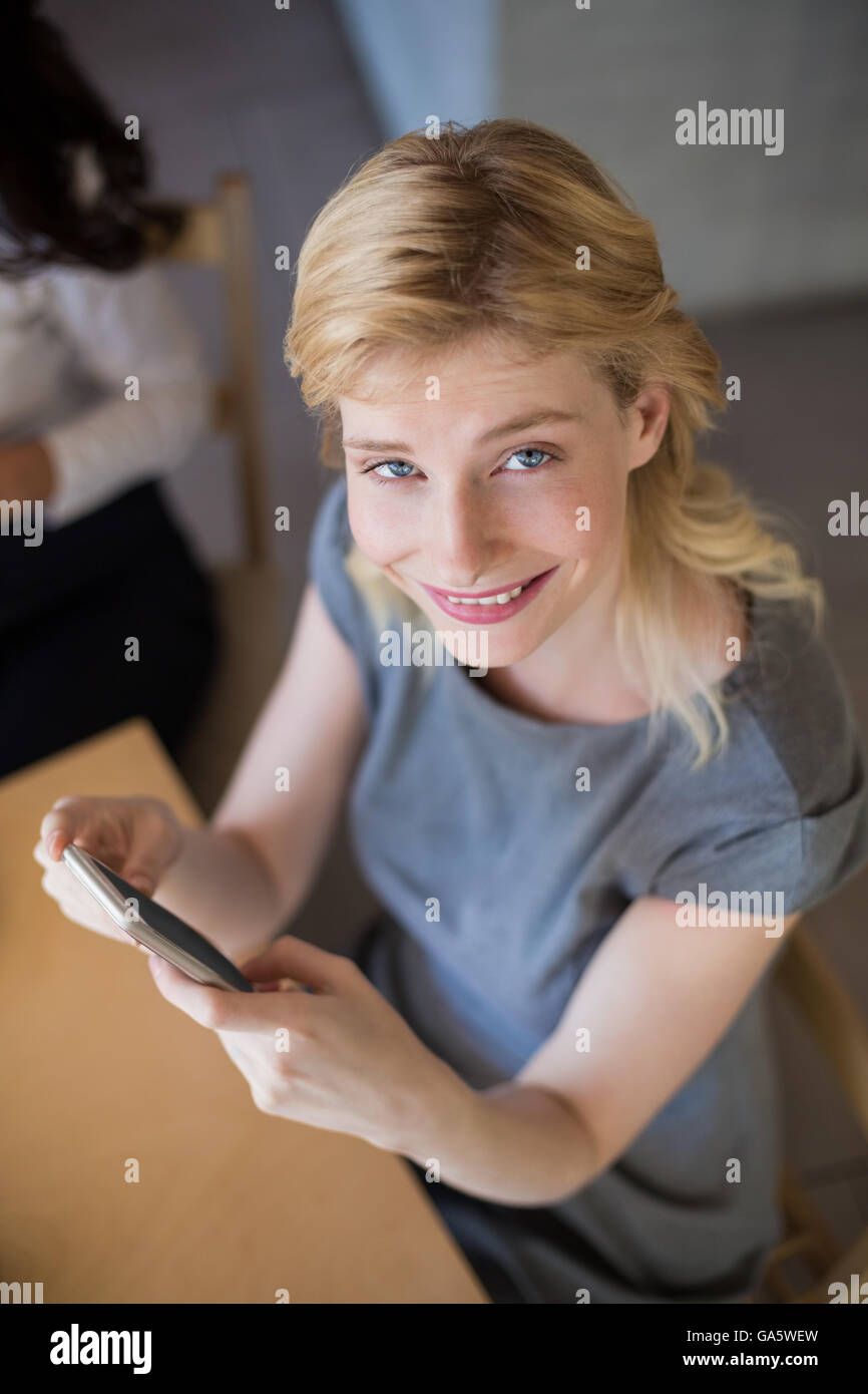 Beautiful woman sitting on table and using mobile phone Stock Photo