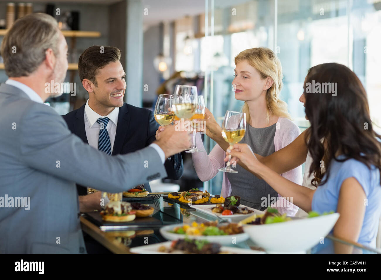 Business colleagues toasting beer glasses while having lunch Stock Photo