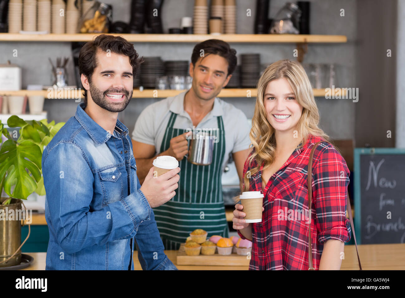 Portrait of smiling couple standing at counter holding cup of coffee Stock Photo