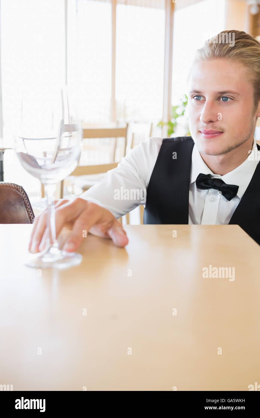 Waiter sitting at table looking at empty glass Stock Photo