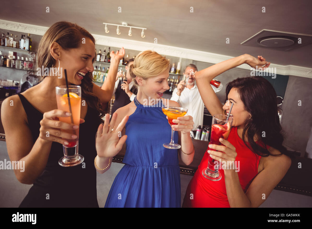 Female friends holding glass of cocktail while dancing Stock Photo