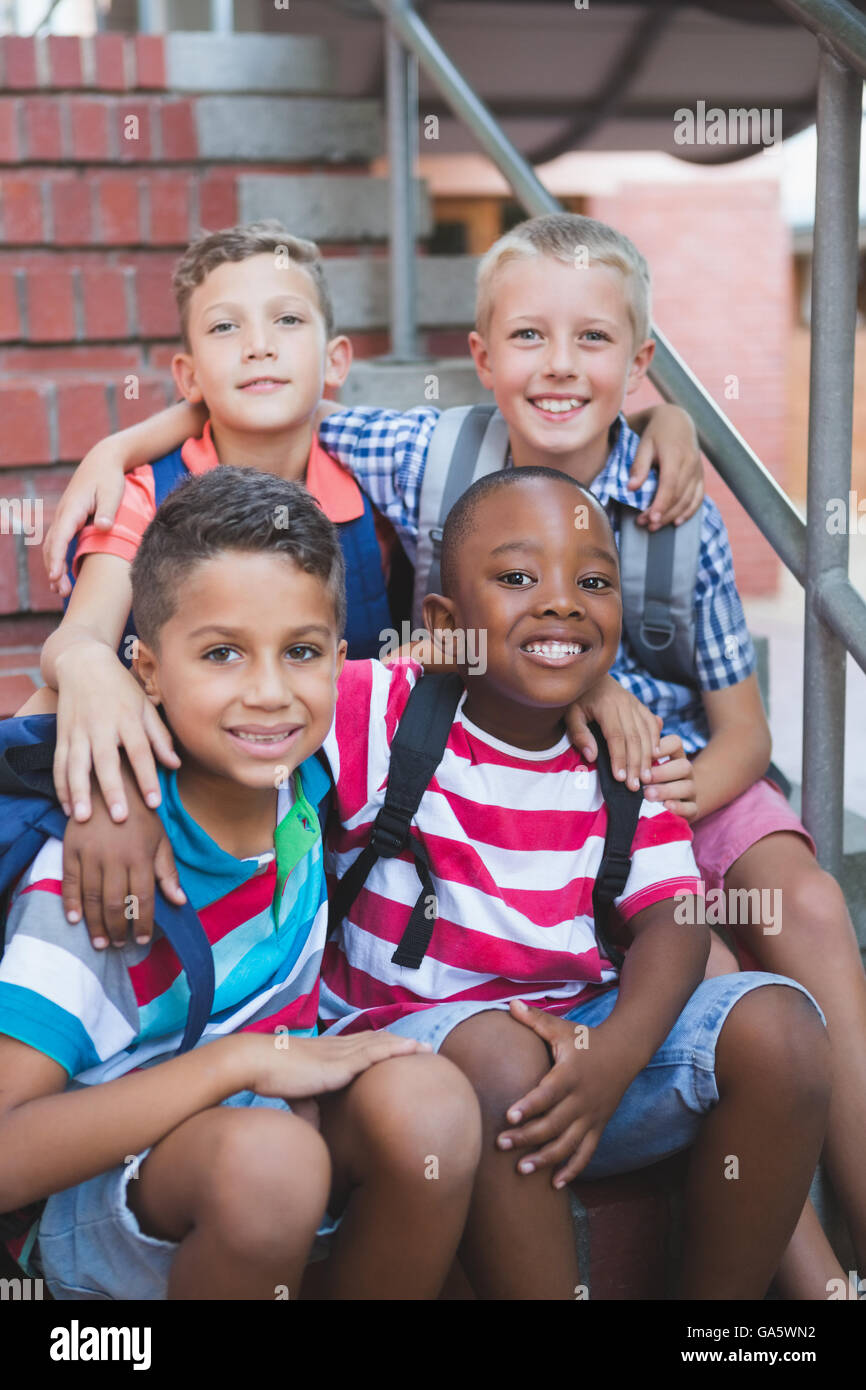 Smiling schoolkids sitting on staircase at school Stock Photo