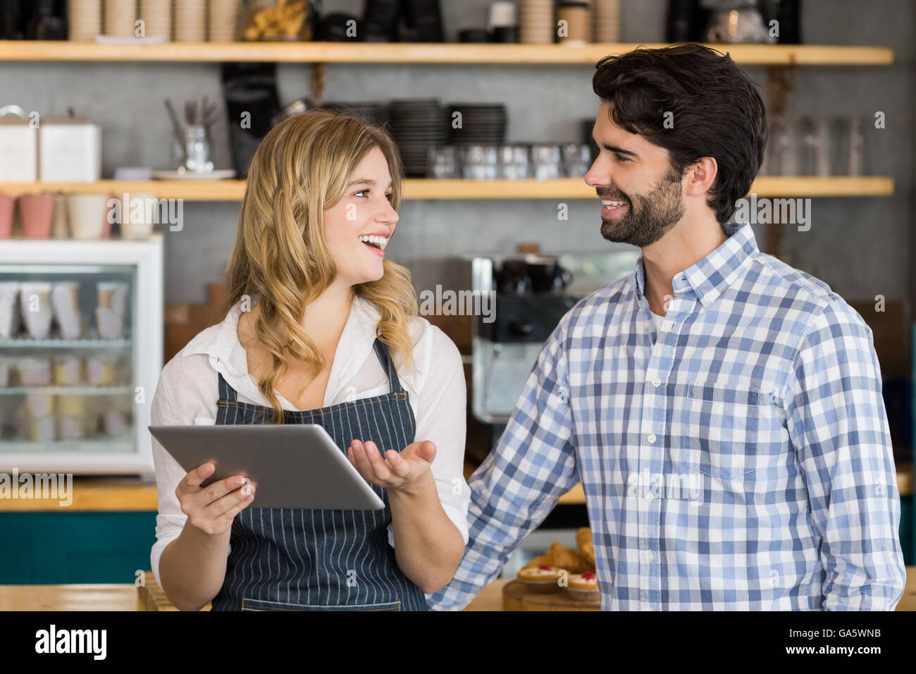 Smiling man and waitress standing at counter using digital tablet Stock Photo