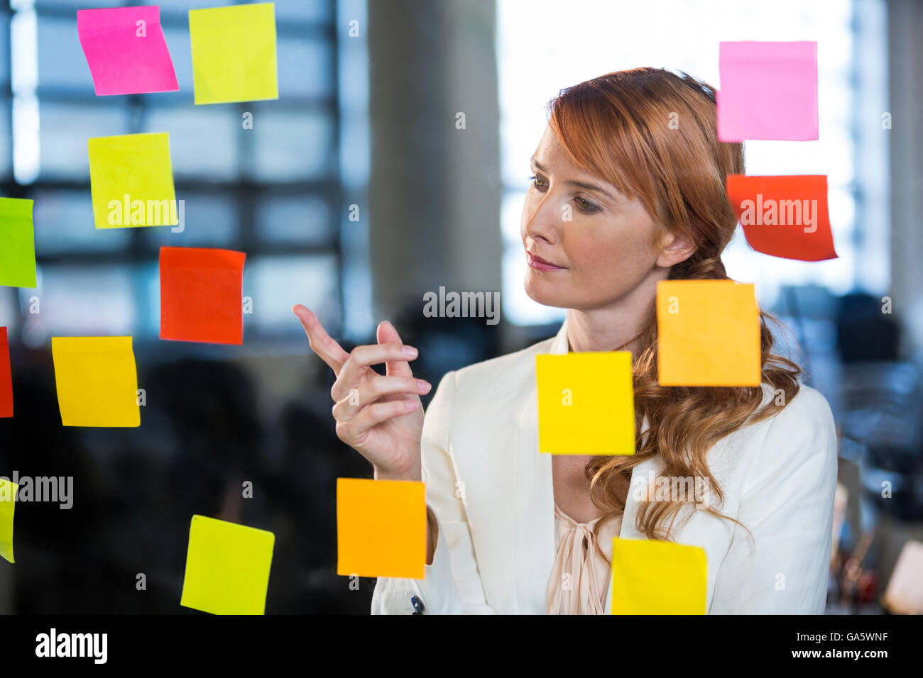 Businesswoman pointing at sticky notes Stock Photo