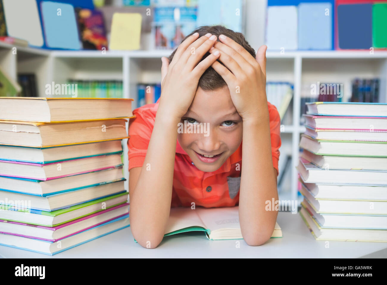 Schoolboy sitting on table and reading book in library Stock Photo - Alamy