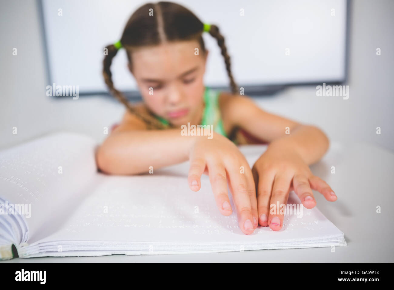 Schoolgirl reading a braille book in classroom Stock Photo