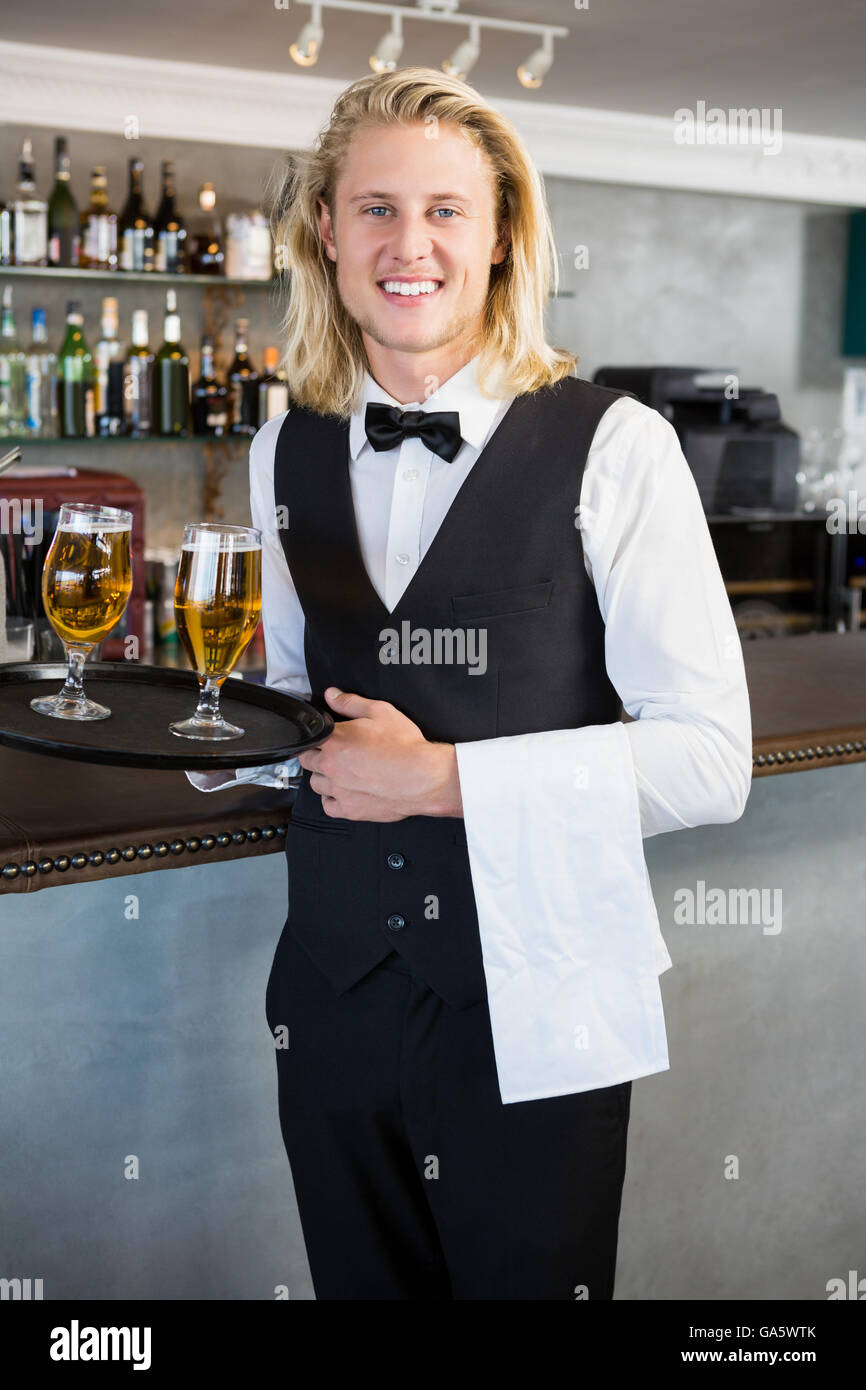 Portrait of waiter holding tray with glasses of beer Stock Photo - Alamy