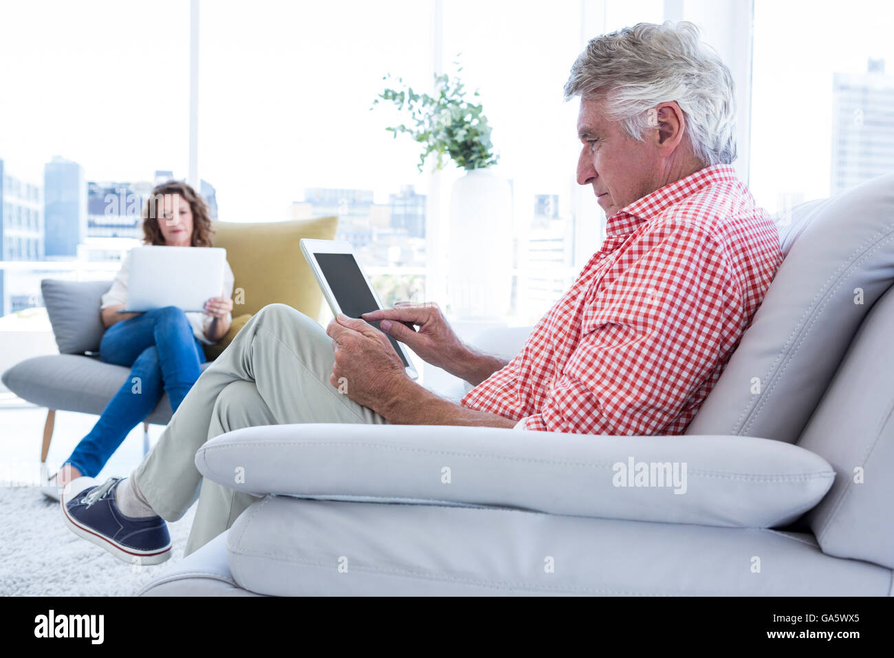 Mature man using tablet computer while sitting Stock Photo