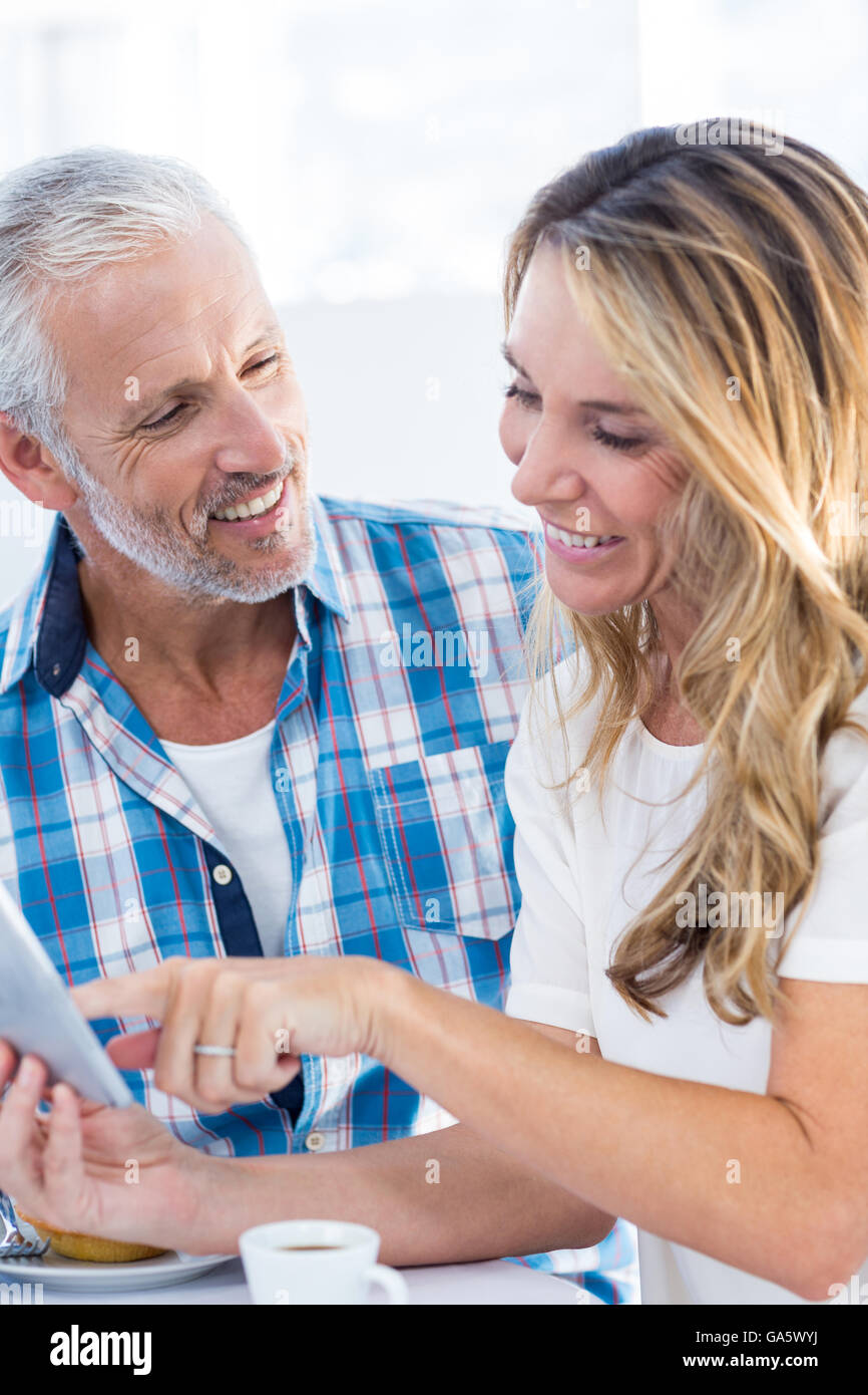 Woman pointing on digital tablet while sitting by husband Stock Photo