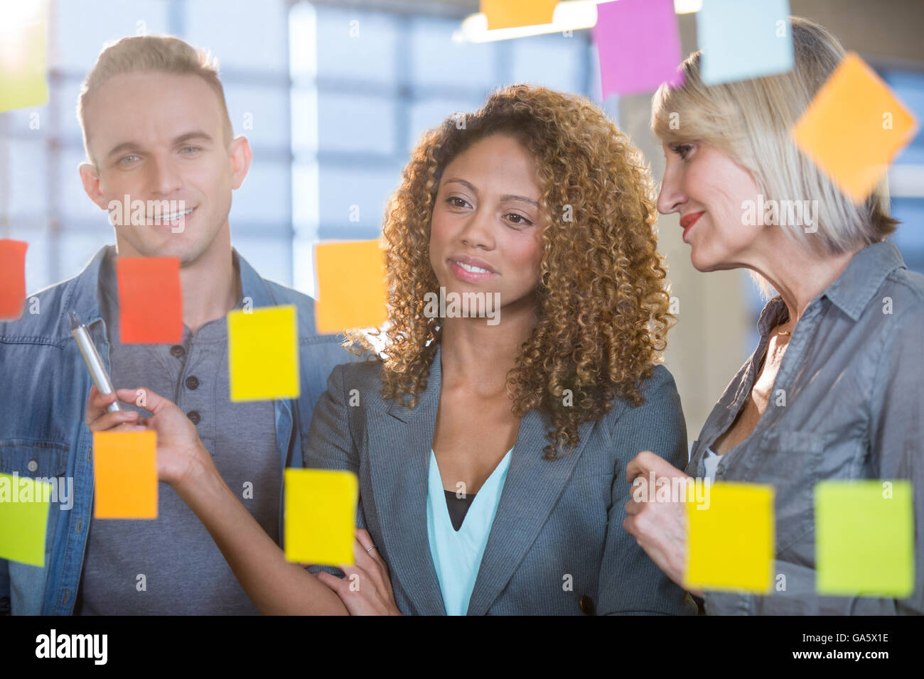 Business people looking at sticky notes stuck to glass Stock Photo