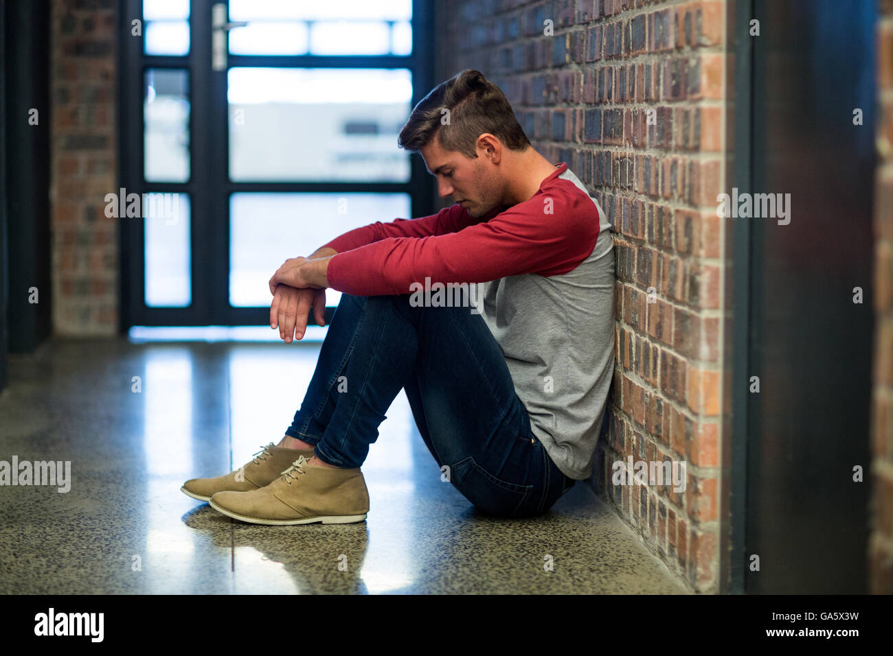 Stressed man sitting in corridor Stock Photo