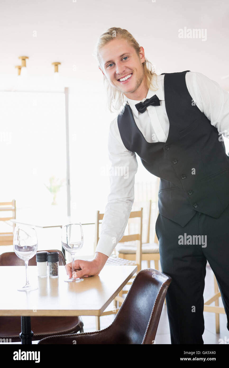 Waiter standing at table with empty glass Stock Photo