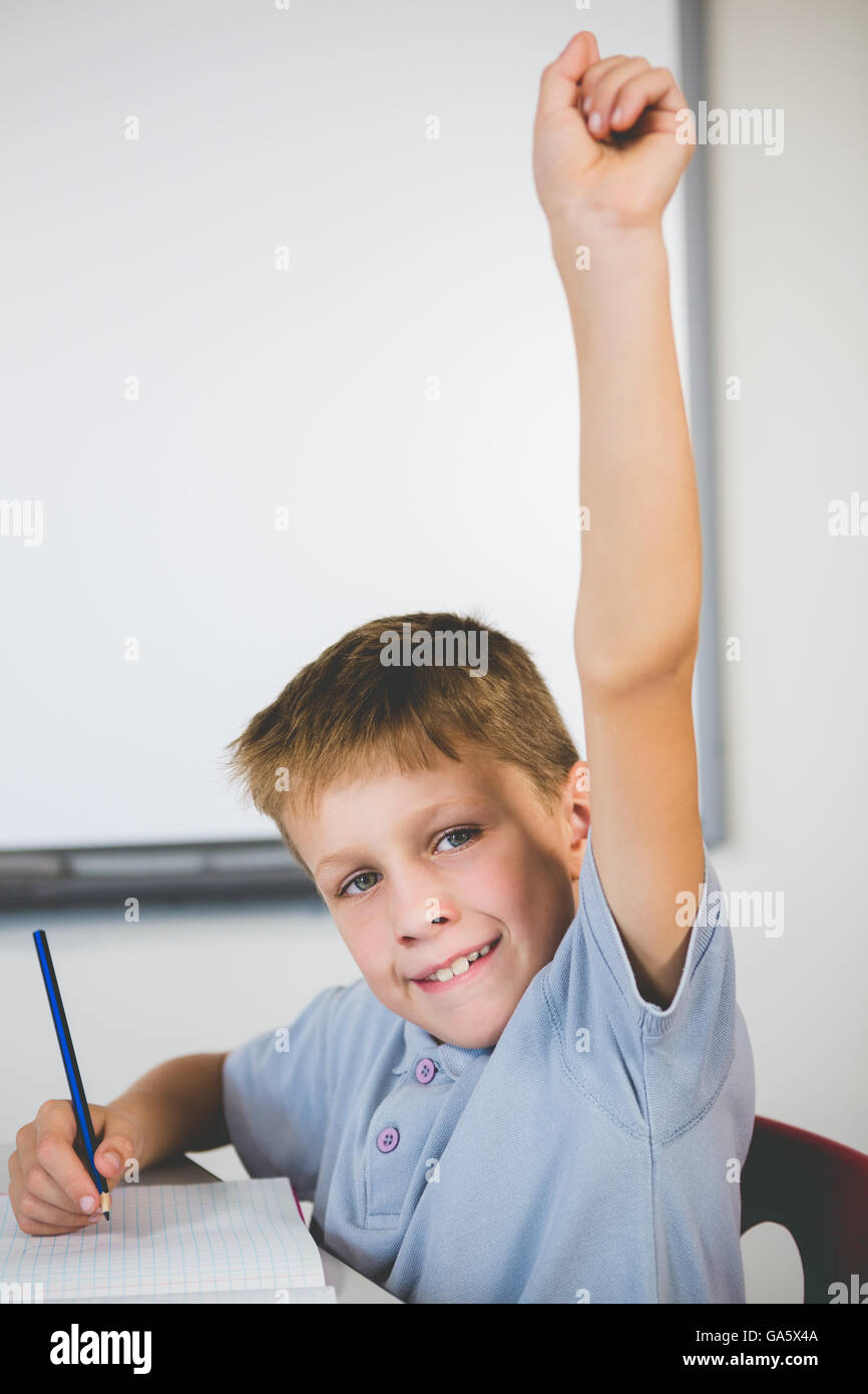 Portrait of schoolboy raising his hand in classroom Stock Photo - Alamy