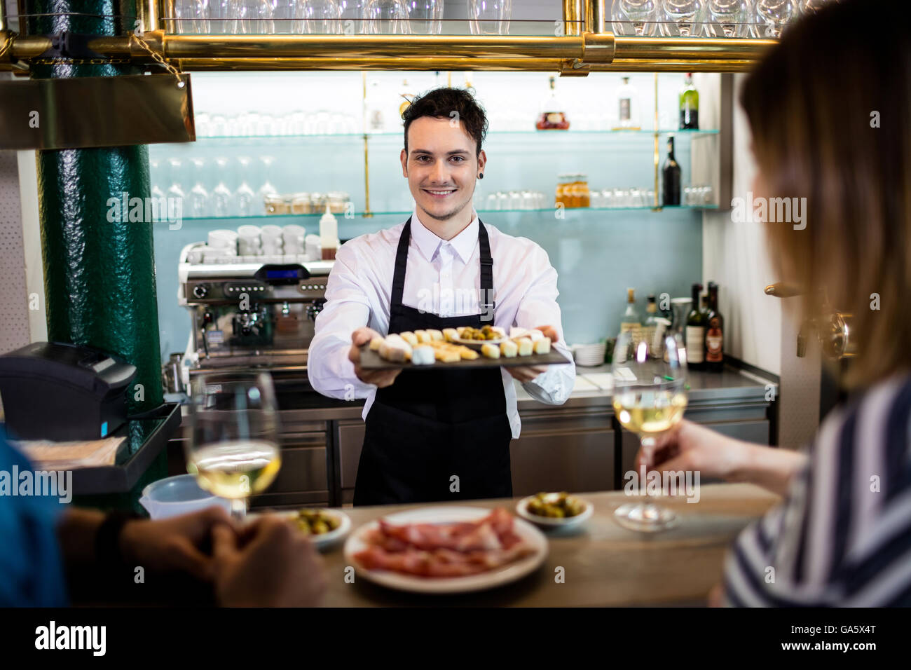 Young bartender serving food to customers at counter Stock Photo