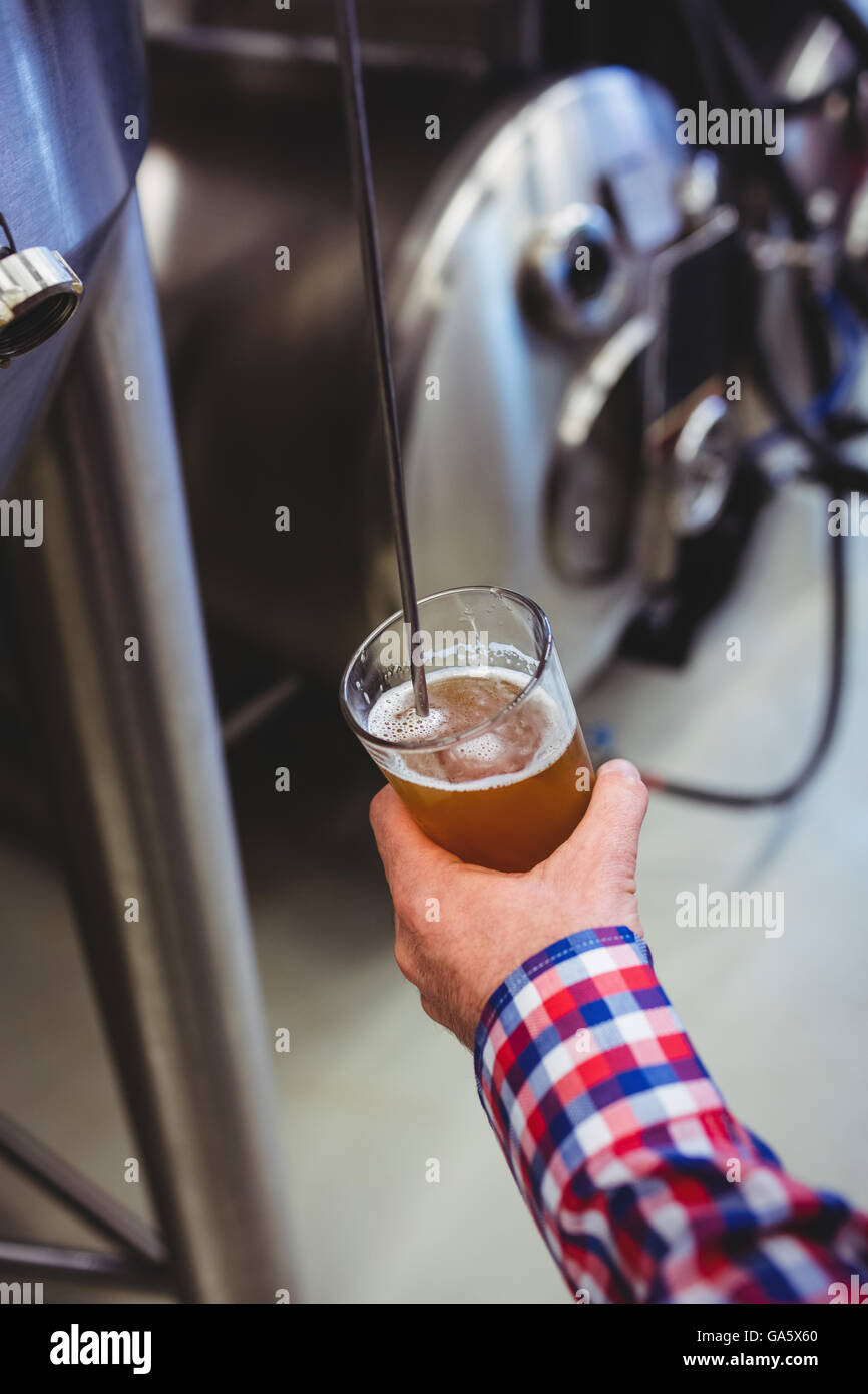 Man holding beer glass by machinery Stock Photo