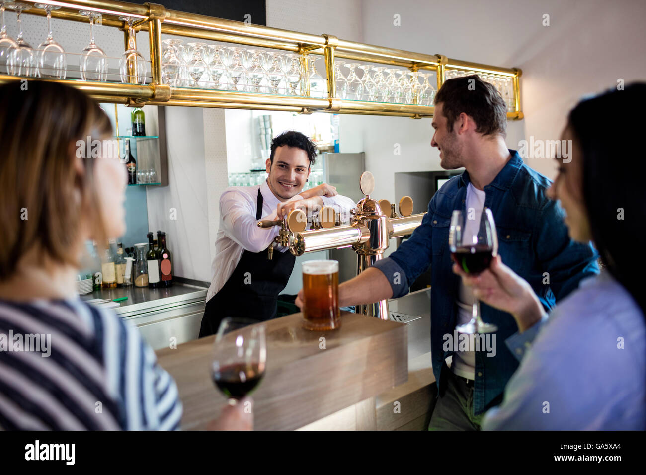 Friends talking to bartender while having drinks Stock Photo