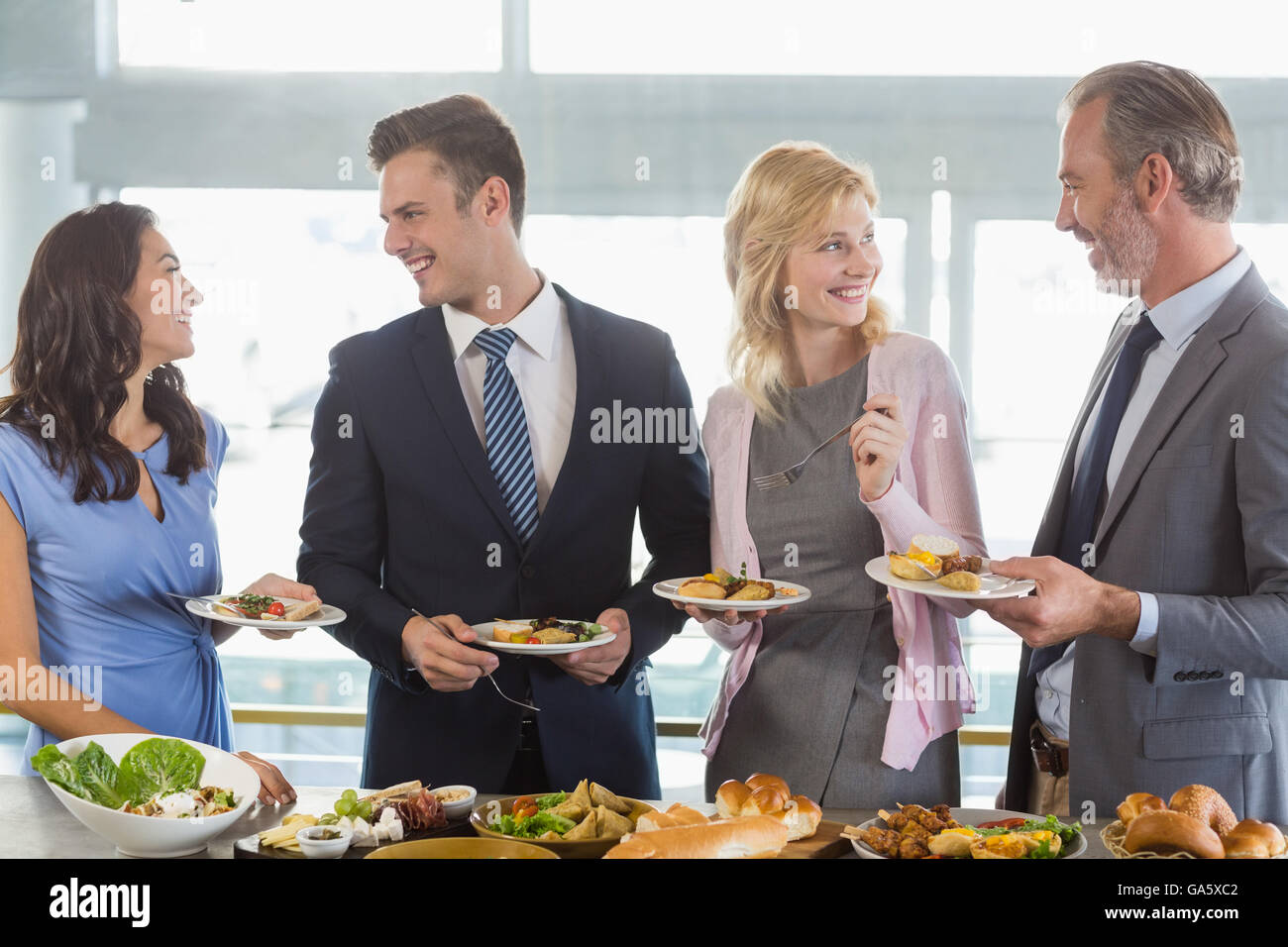 Business colleagues interacting while serving themselves at buffet ...