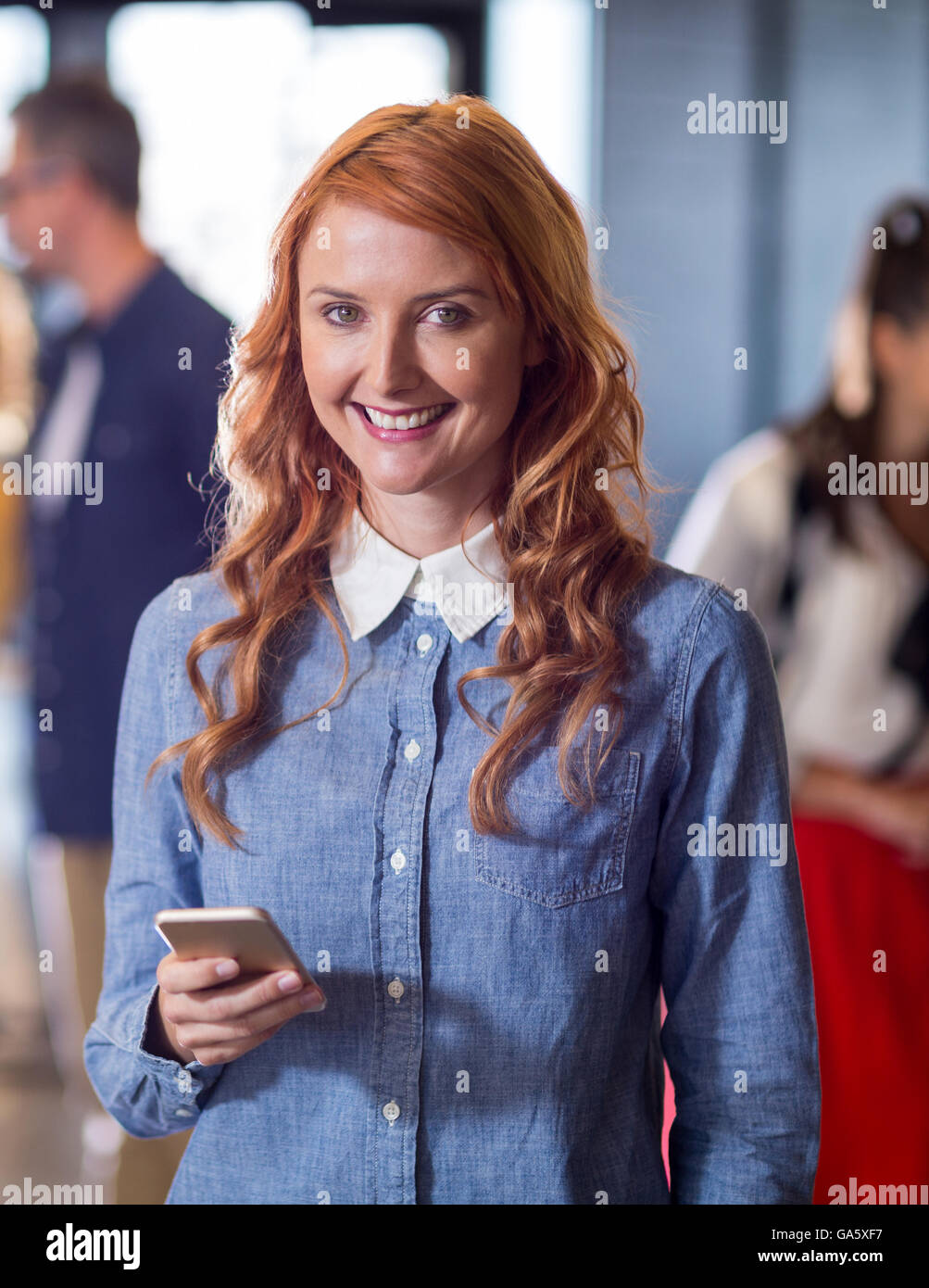 Portrait of smiling woman holding mobile phone in office Stock Photo