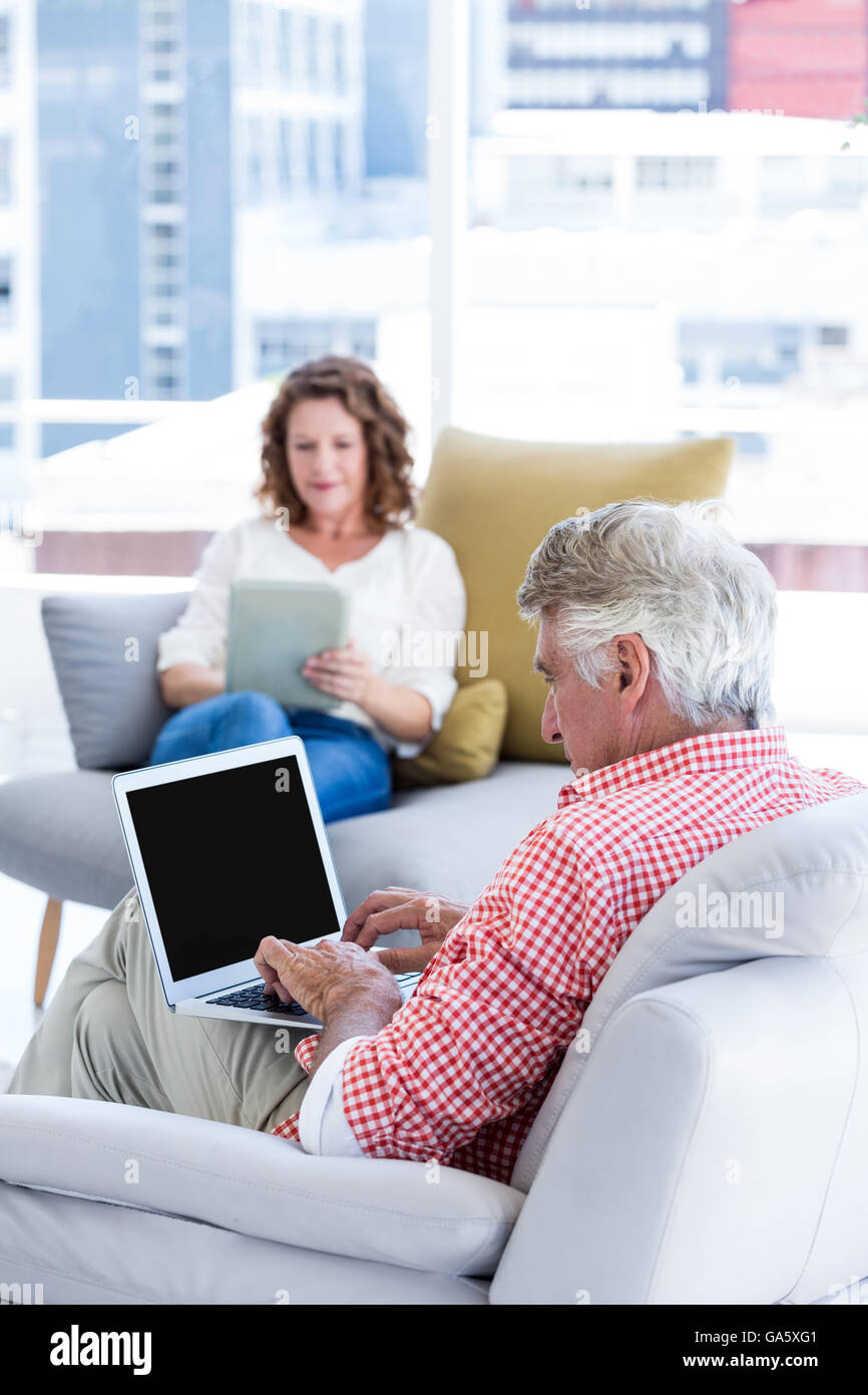 Mature man typing on laptop while sitting by woman Stock Photo