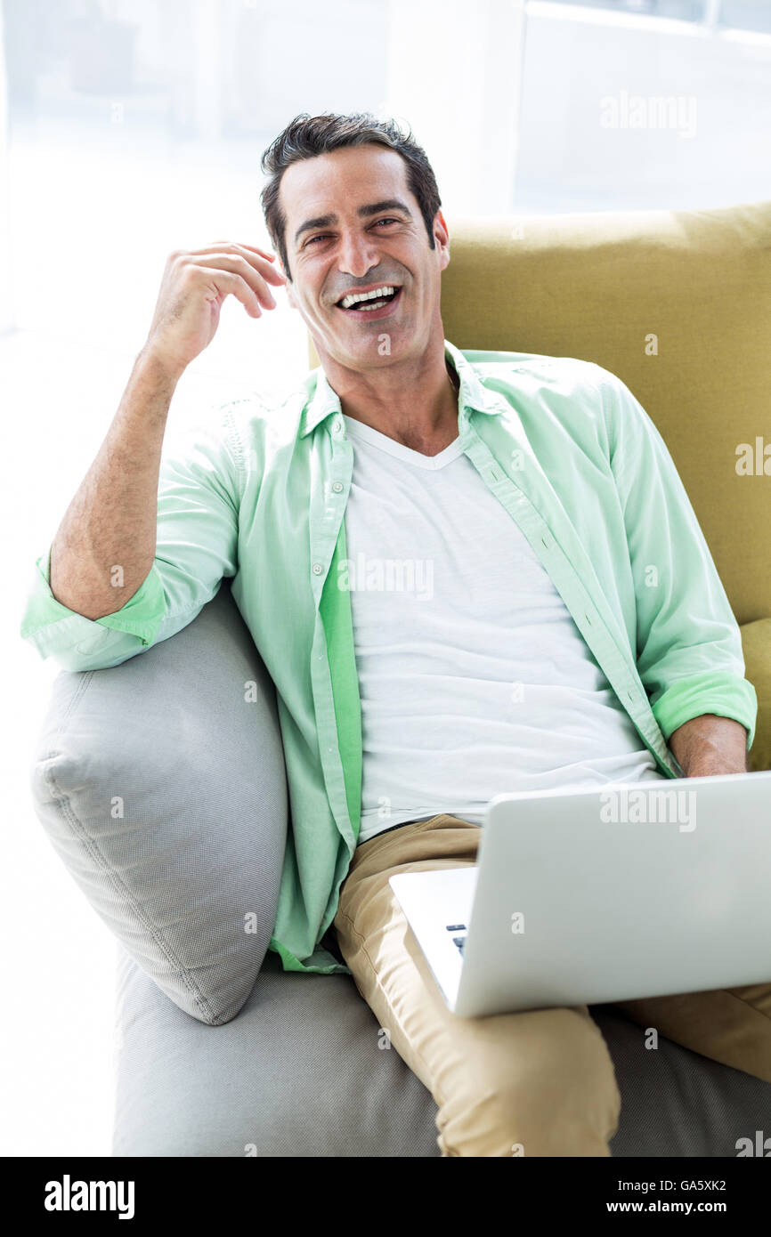 Happy man sitting with laptop on sofa Stock Photo