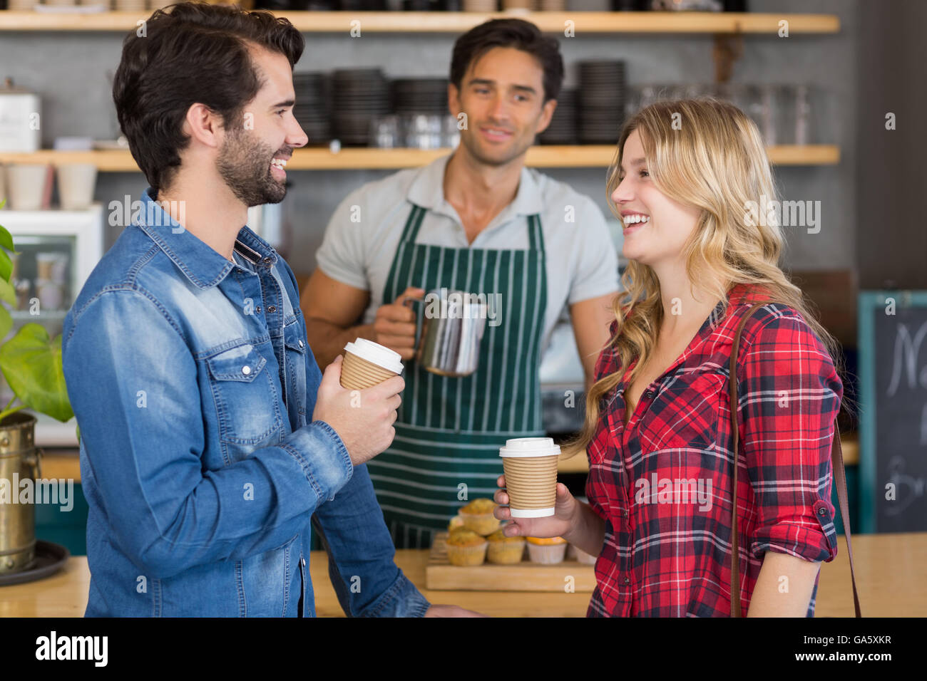 Happy couple standing at counter holding cup of coffee Stock Photo