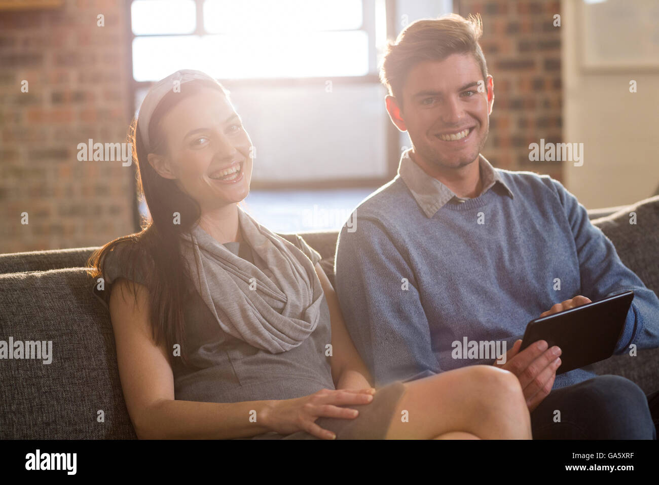 Young colleagues sitting on sofa in office Stock Photo