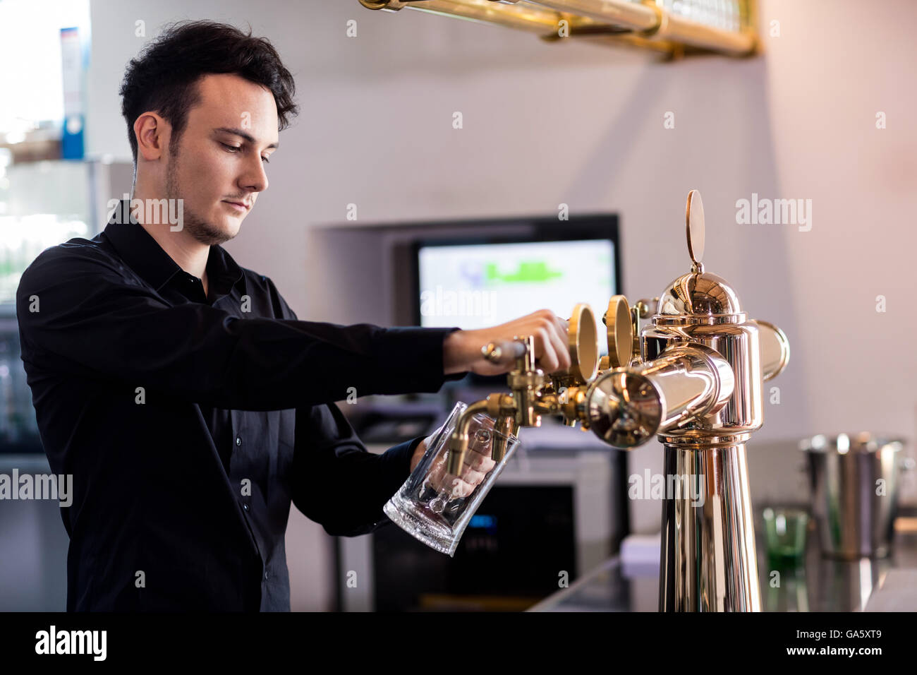 Barkeeper pouring beer in glass at counter Stock Photo