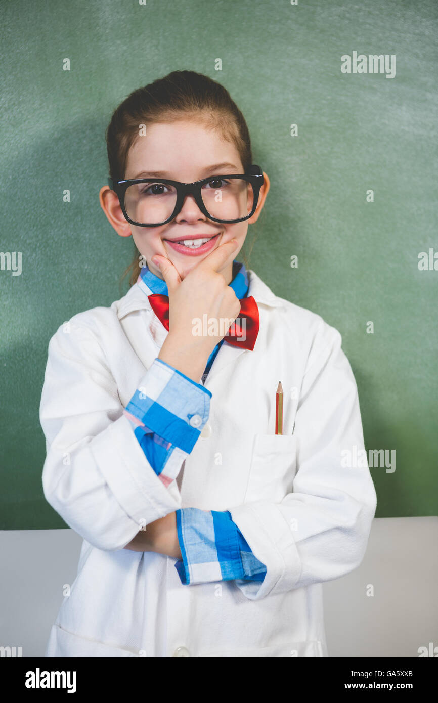 Portrait of smiling girl standing with hand on chin in classroom Stock Photo