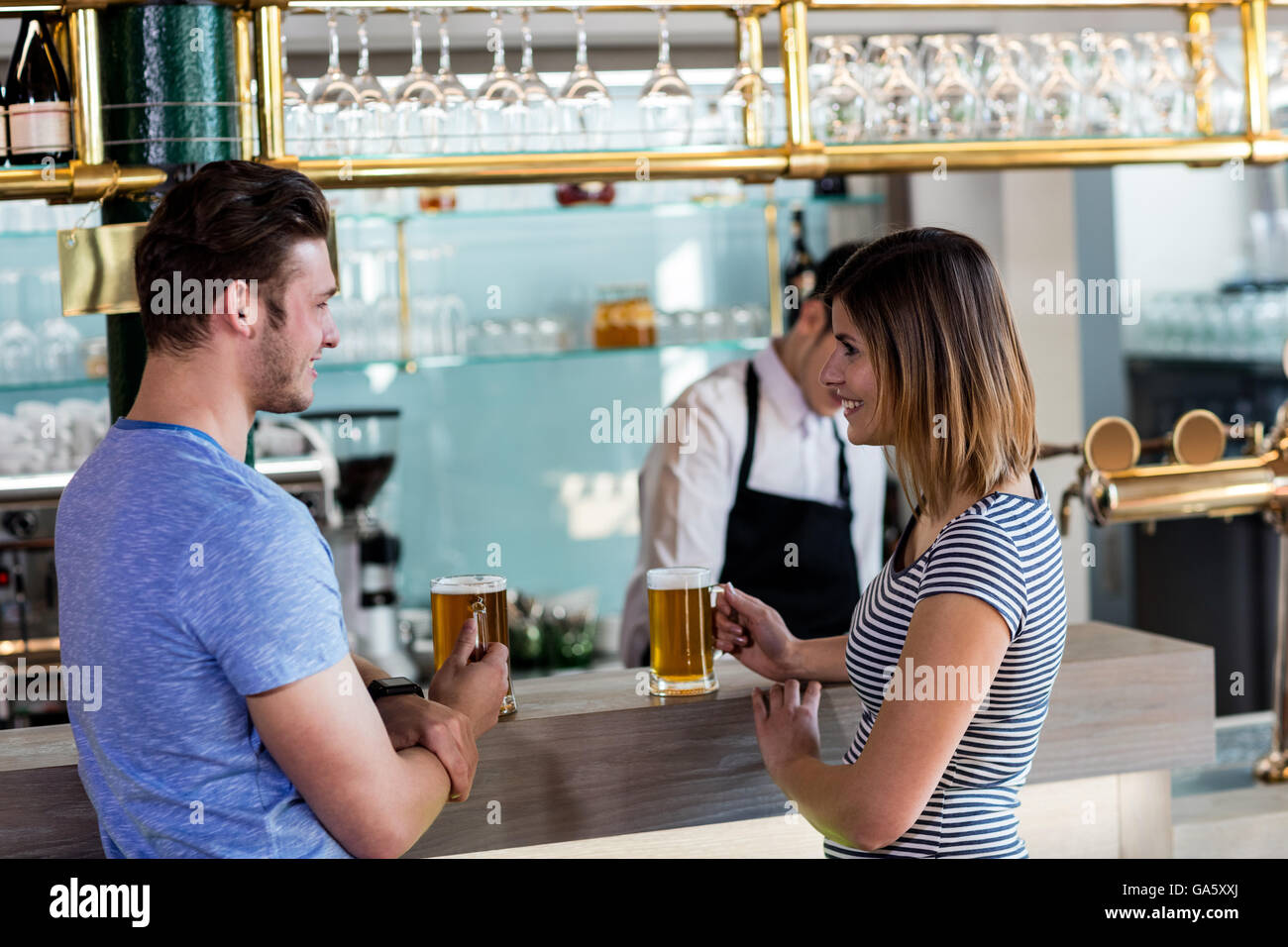 Couple smiling while having beer at counter Stock Photo
