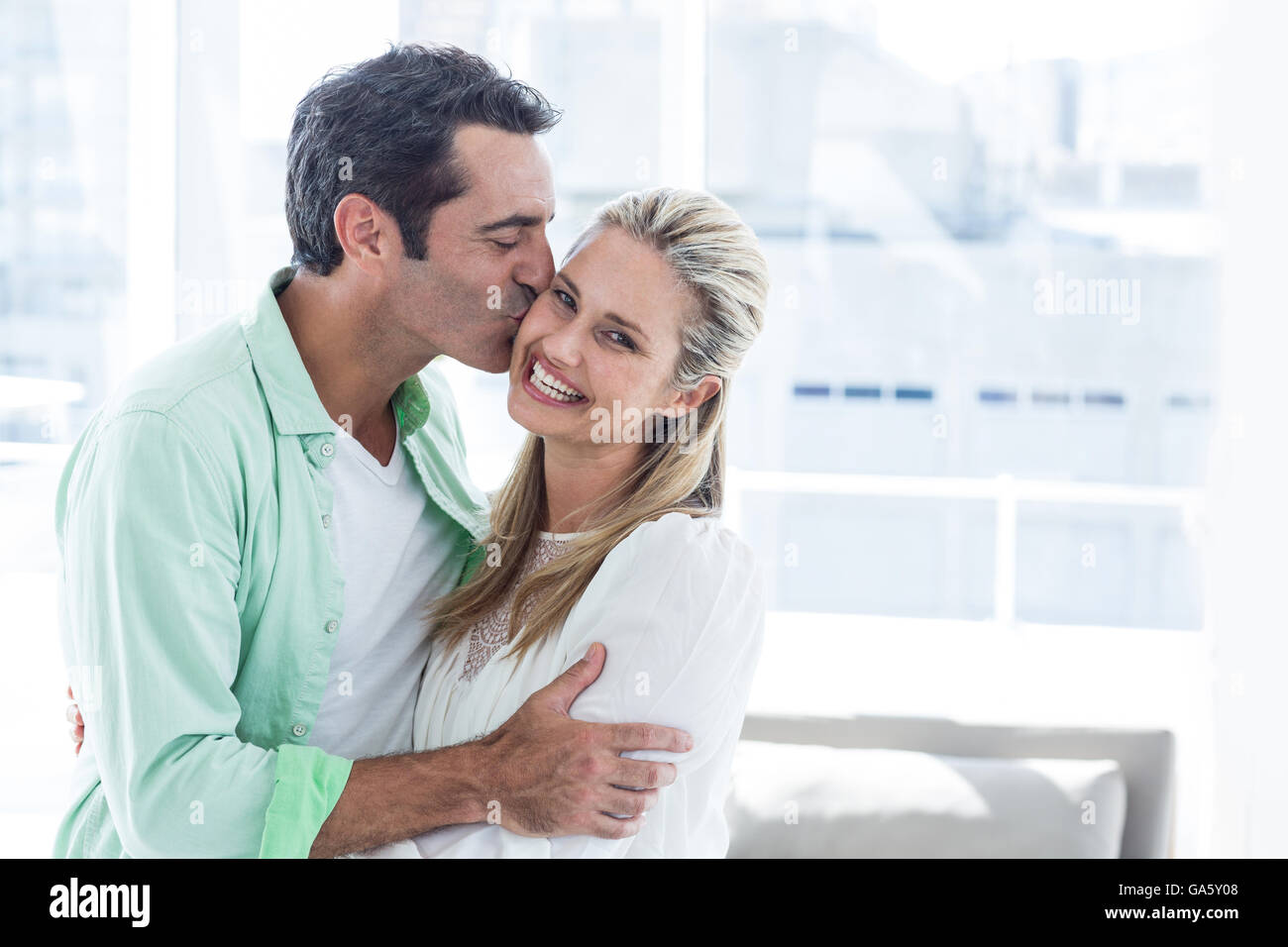 Mid adult man kissing woman at home Stock Photo