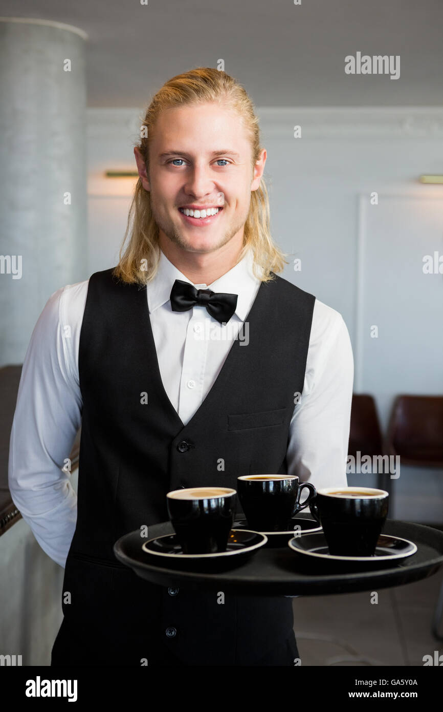 Waiter holding a tray with coffee cups in restaurant Stock Photo