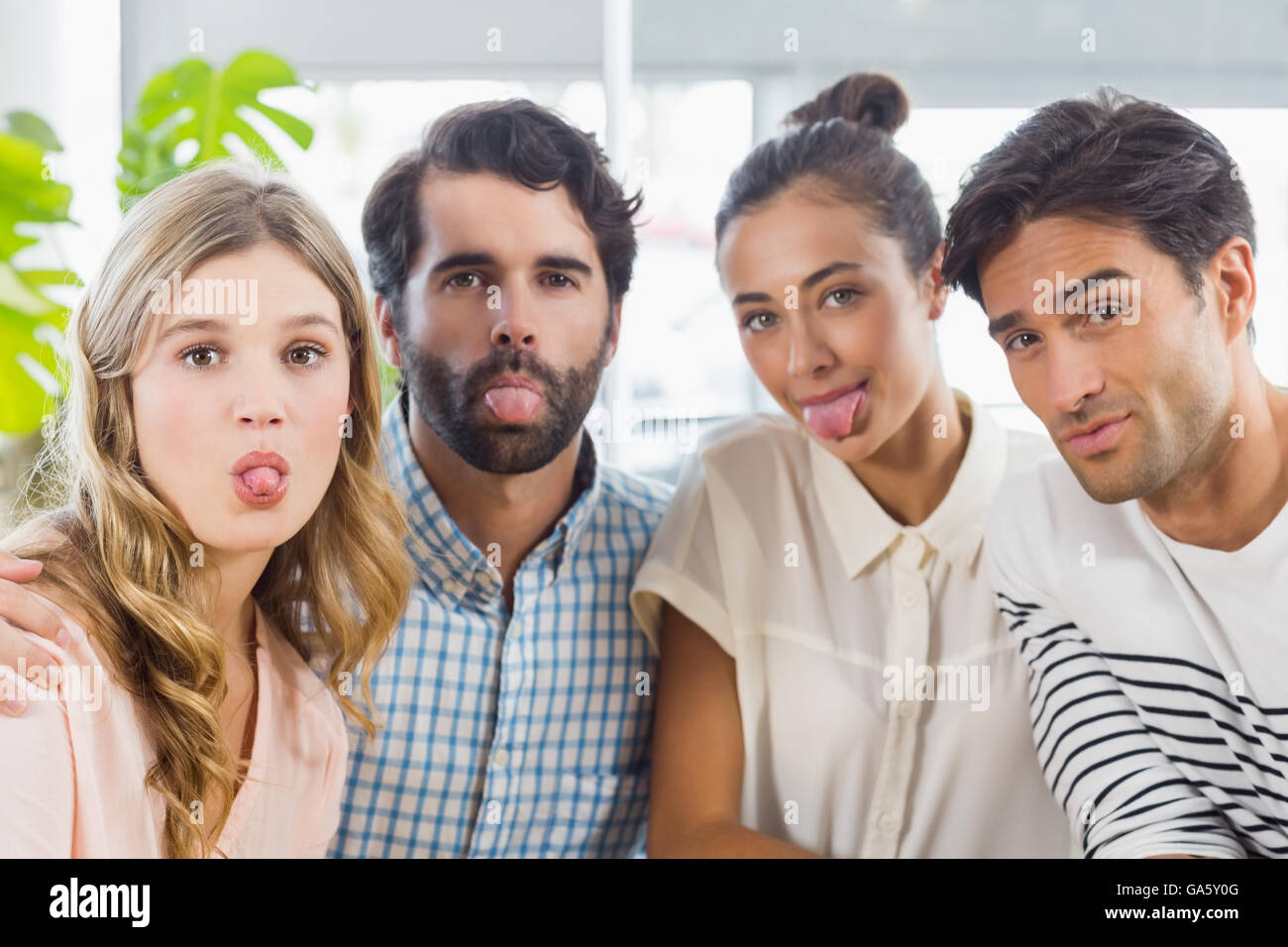 Portrait of friends sticking out tongue Stock Photo