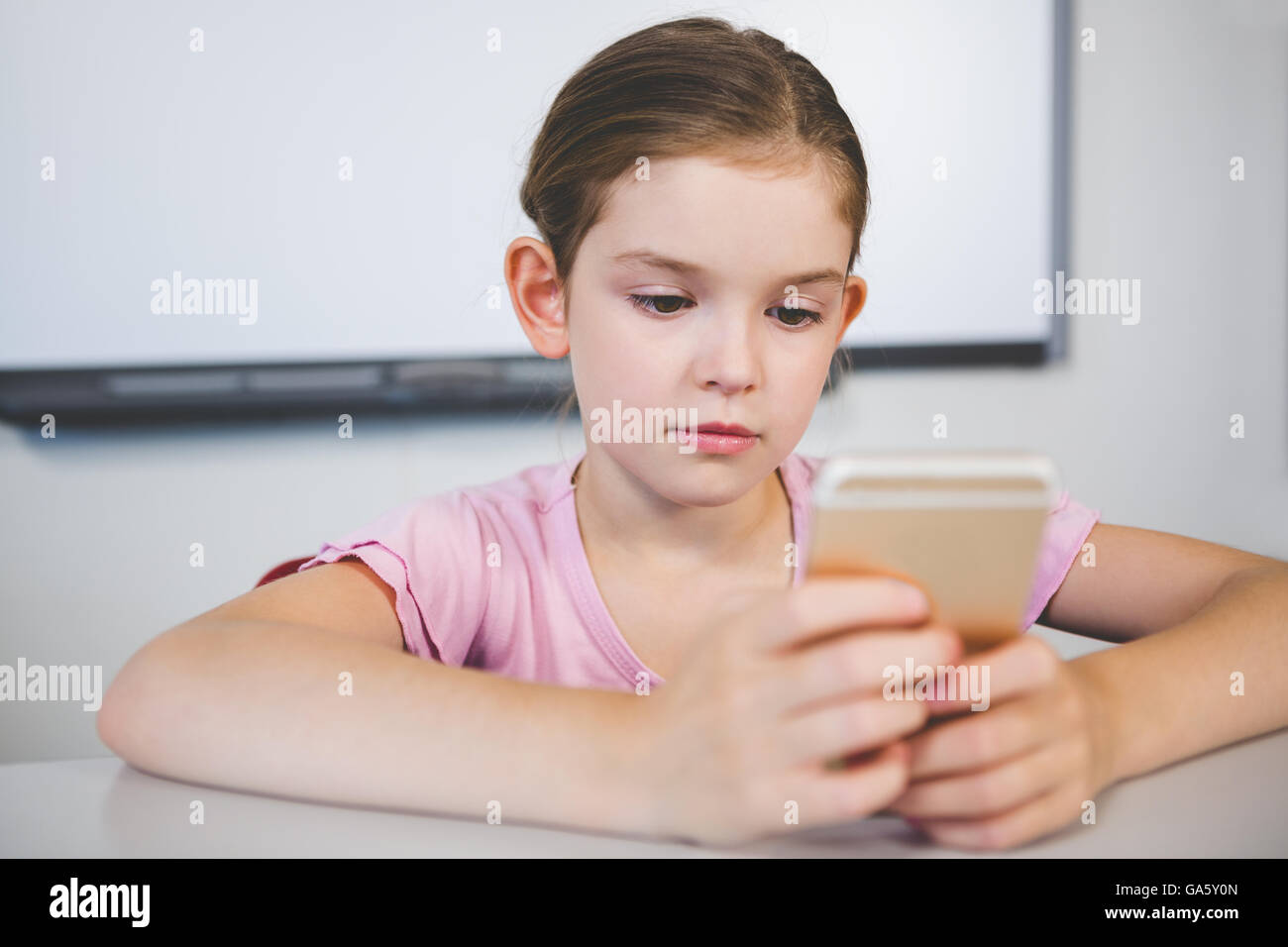 Schoolgirl using mobile phone in classroom Stock Photo