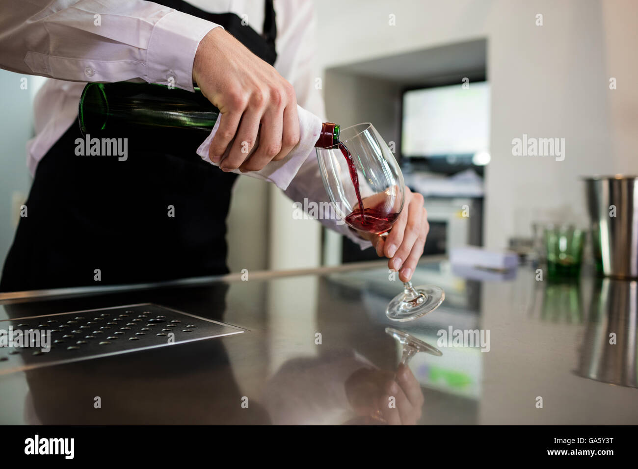Bartender pouring wine in glass at bar counter Stock Photo