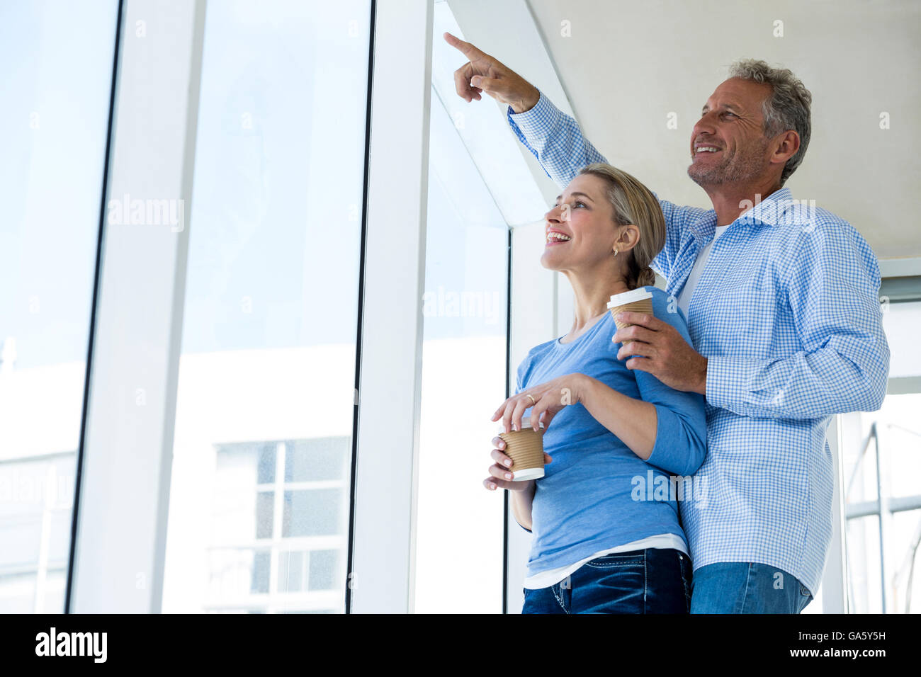 Smiling man pointing while standing by woman Stock Photo