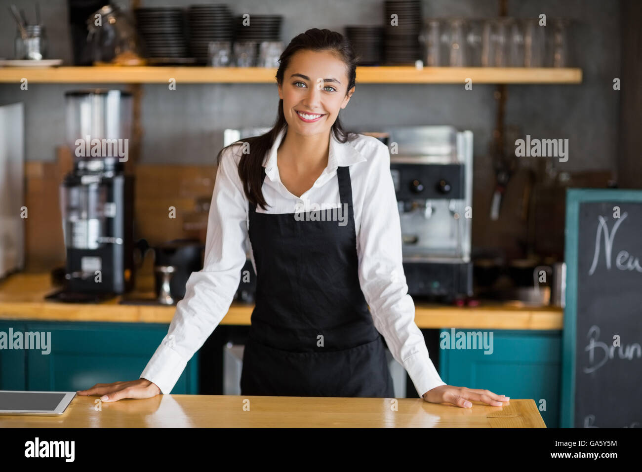 Portrait of smiling waitress standing at counter Stock Photo