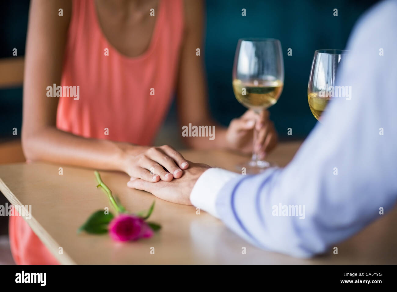 Mid section of couple holding hands while having glass of wine Stock Photo